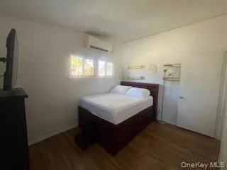 Bedroom with a wall mounted AC and wood finished floors Bedroom with a wall mounted AC and wood finished floors