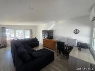 Living room featuring wood finished floors and an AC wall unit Living room featuring wood finished floors and an AC wall unit