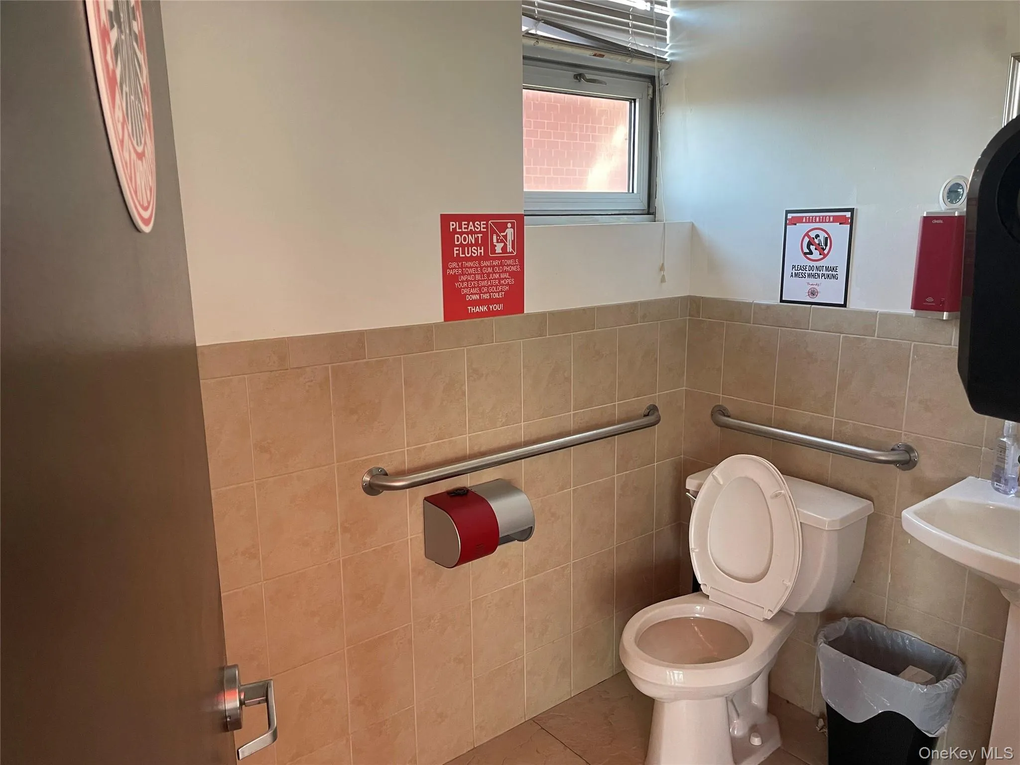Bathroom featuring tile patterned floors, toilet, and tile walls Bathroom featuring tile patterned floors, toilet, and tile walls