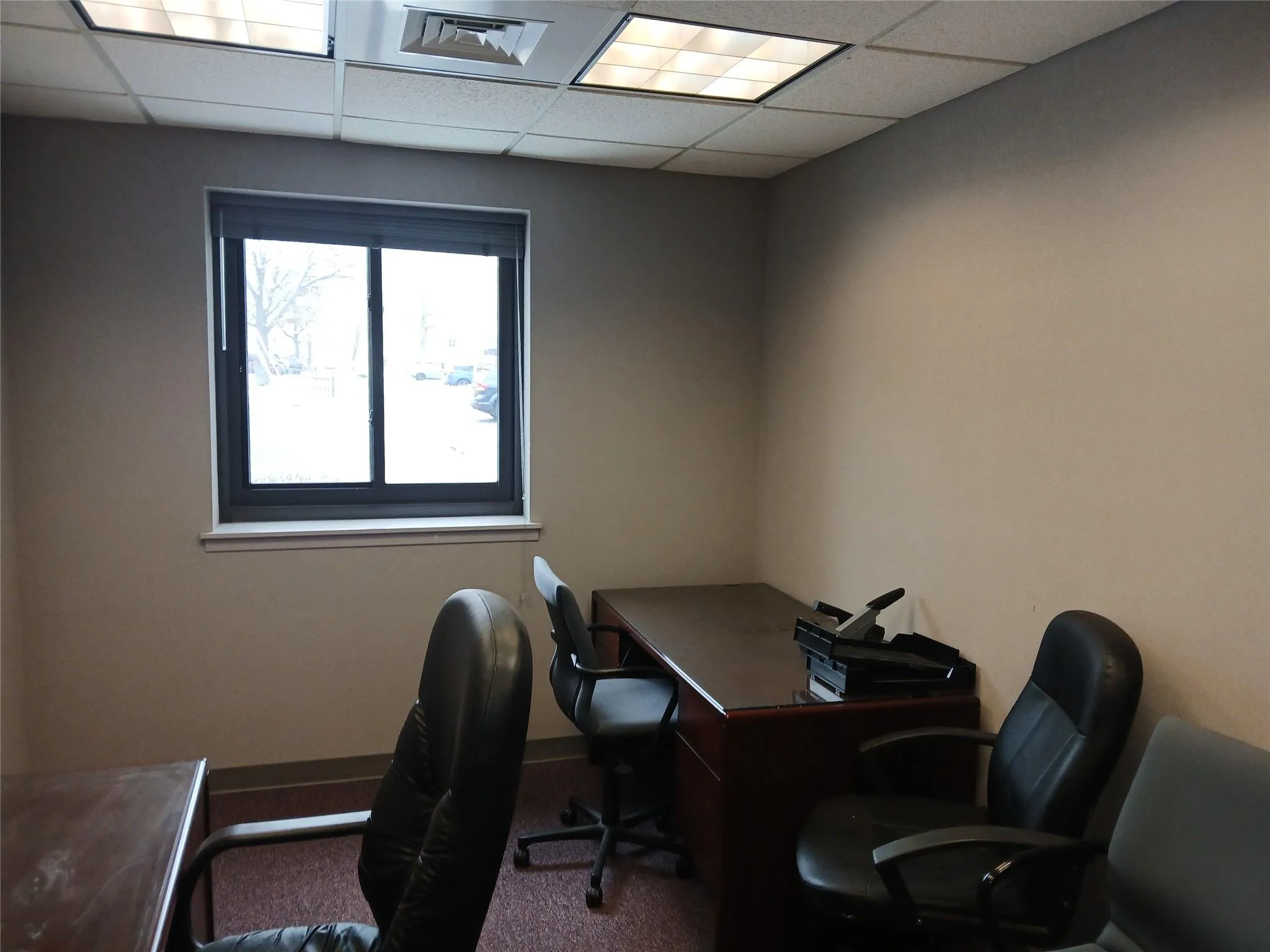 Office area with a paneled ceiling and carpet flooring Office area with a paneled ceiling and carpet flooring