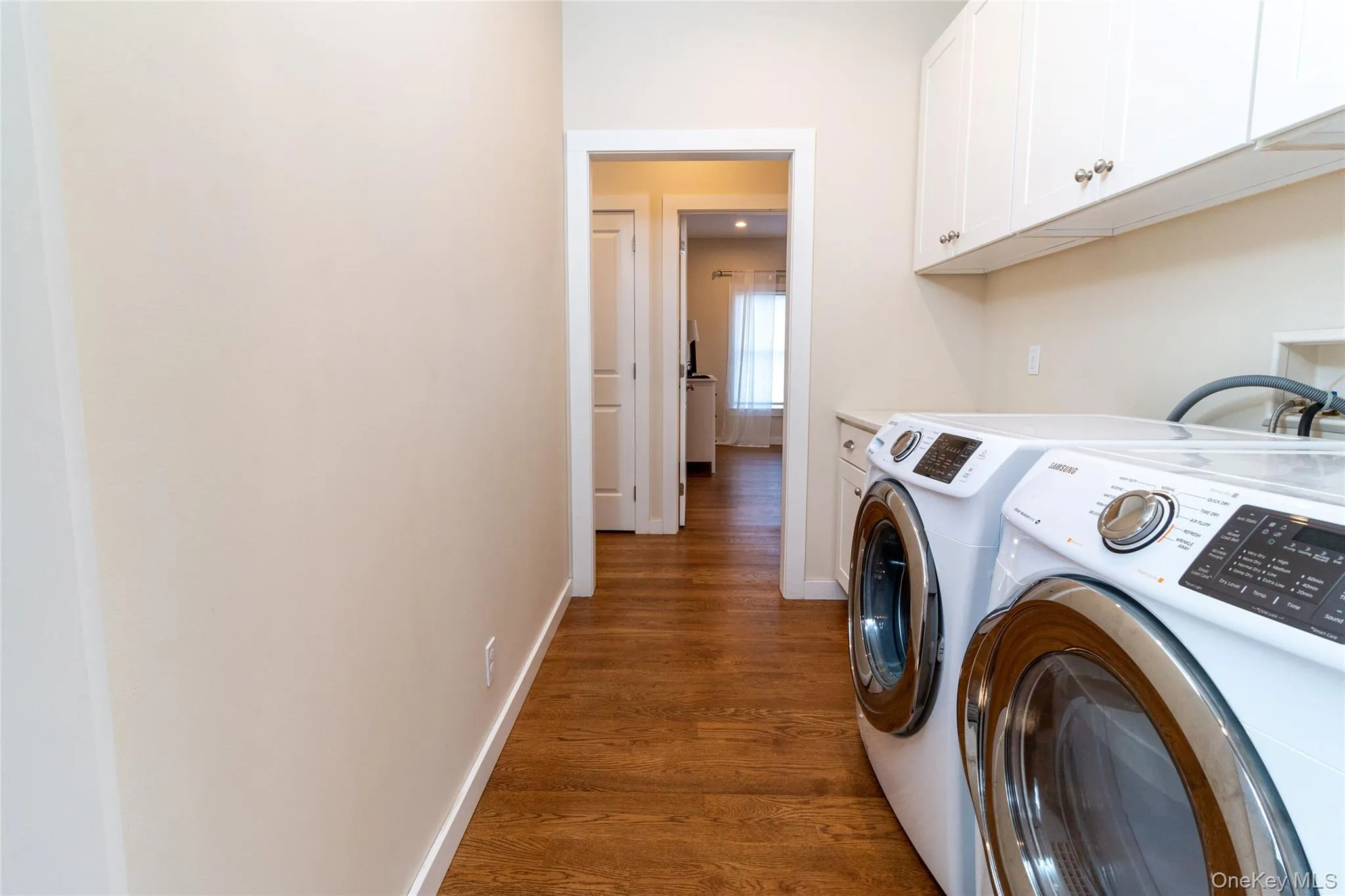Washroom featuring cabinets, dark hardwood / wood-style flooring, and separate washer and dryer Washroom featuring cabinets, dark hardwood / wood-style flooring, and separate washer and dryer