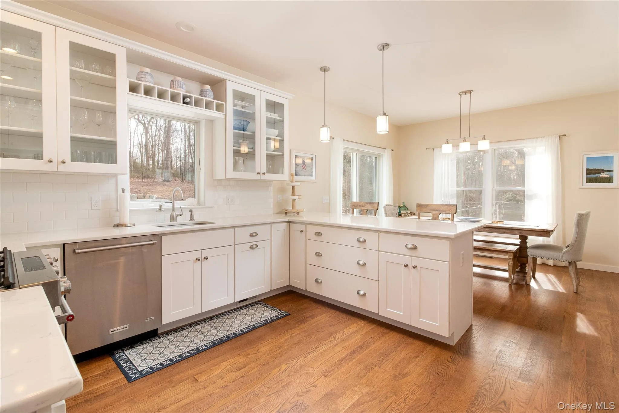 Kitchen with pendant lighting, sink, hardwood / wood-style flooring, white cabinetry, and stainless steel dishwasher Kitchen with pendant lighting, sink, hardwood / wood-style flooring, white cabinetry, and stainless steel dishwasher