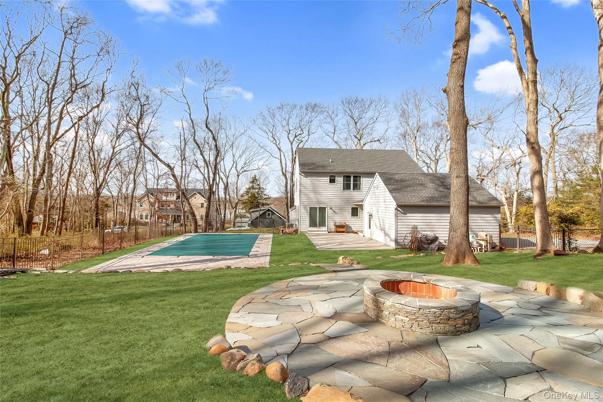 Back of house featuring a swimming pool side deck, an outdoor fire pit, a yard, and a patio area Back of house featuring a swimming pool side deck, an outdoor fire pit, a yard, and a patio area