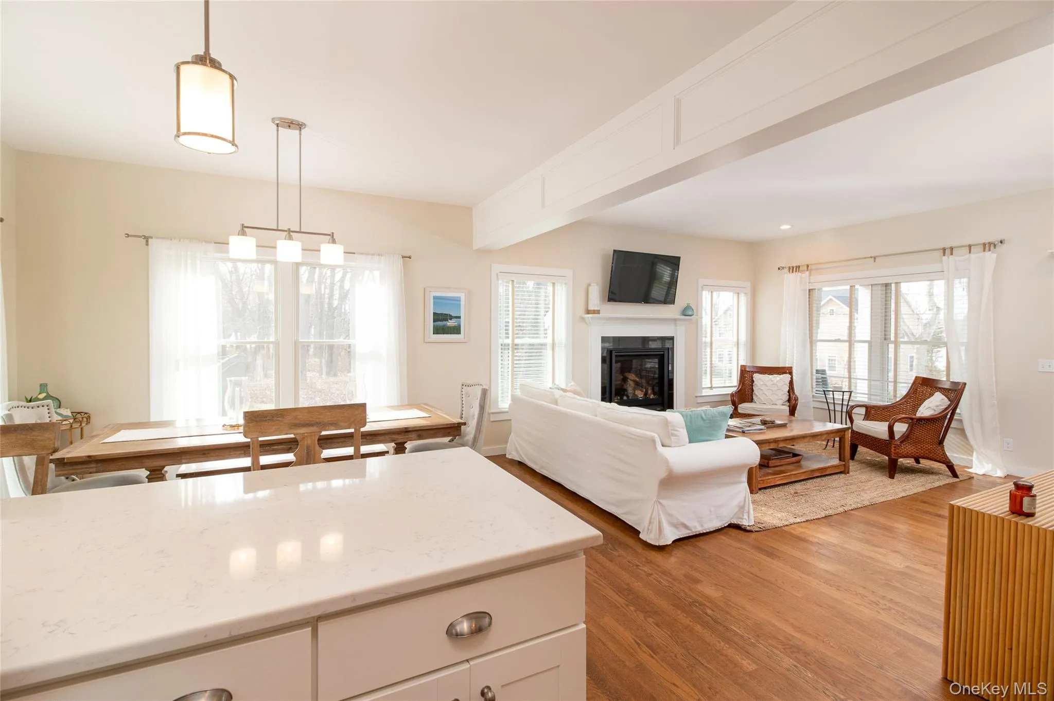 Kitchen featuring white cabinetry, light stone countertops, hanging light fixtures, and light wood-type flooring Kitchen featuring white cabinetry, light stone countertops, hanging light fixtures, and light wood-type flooring