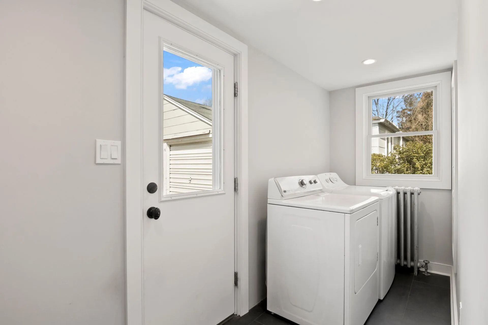 Laundry room featuring dark tile patterned flooring and washing machine and clothes dryer Laundry room featuring dark tile patterned flooring and washing machine and clothes dryer