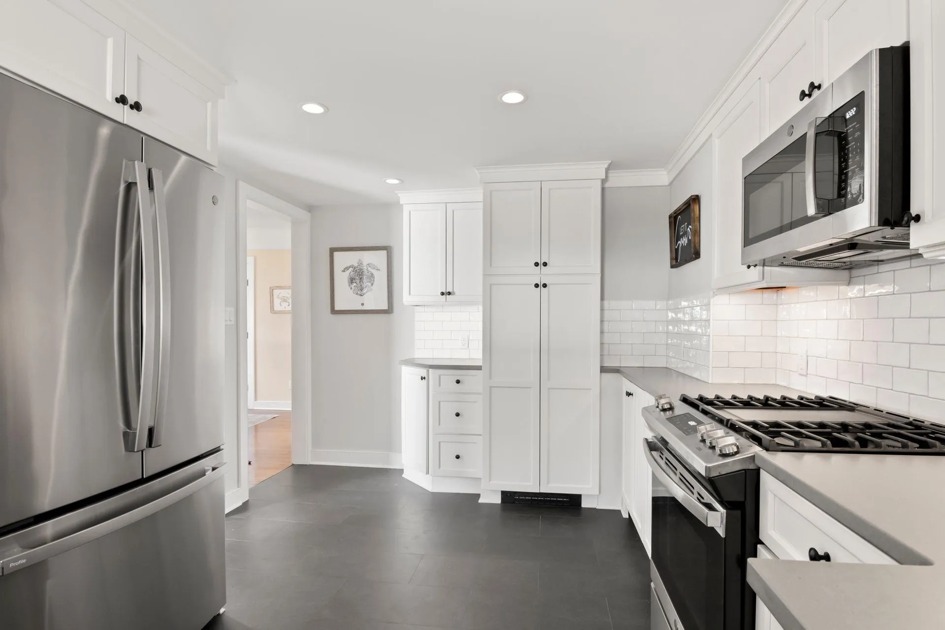 Kitchen featuring decorative backsplash, white cabinets, and appliances with stainless steel finishes Kitchen featuring decorative backsplash, white cabinets, and appliances with stainless steel finishes