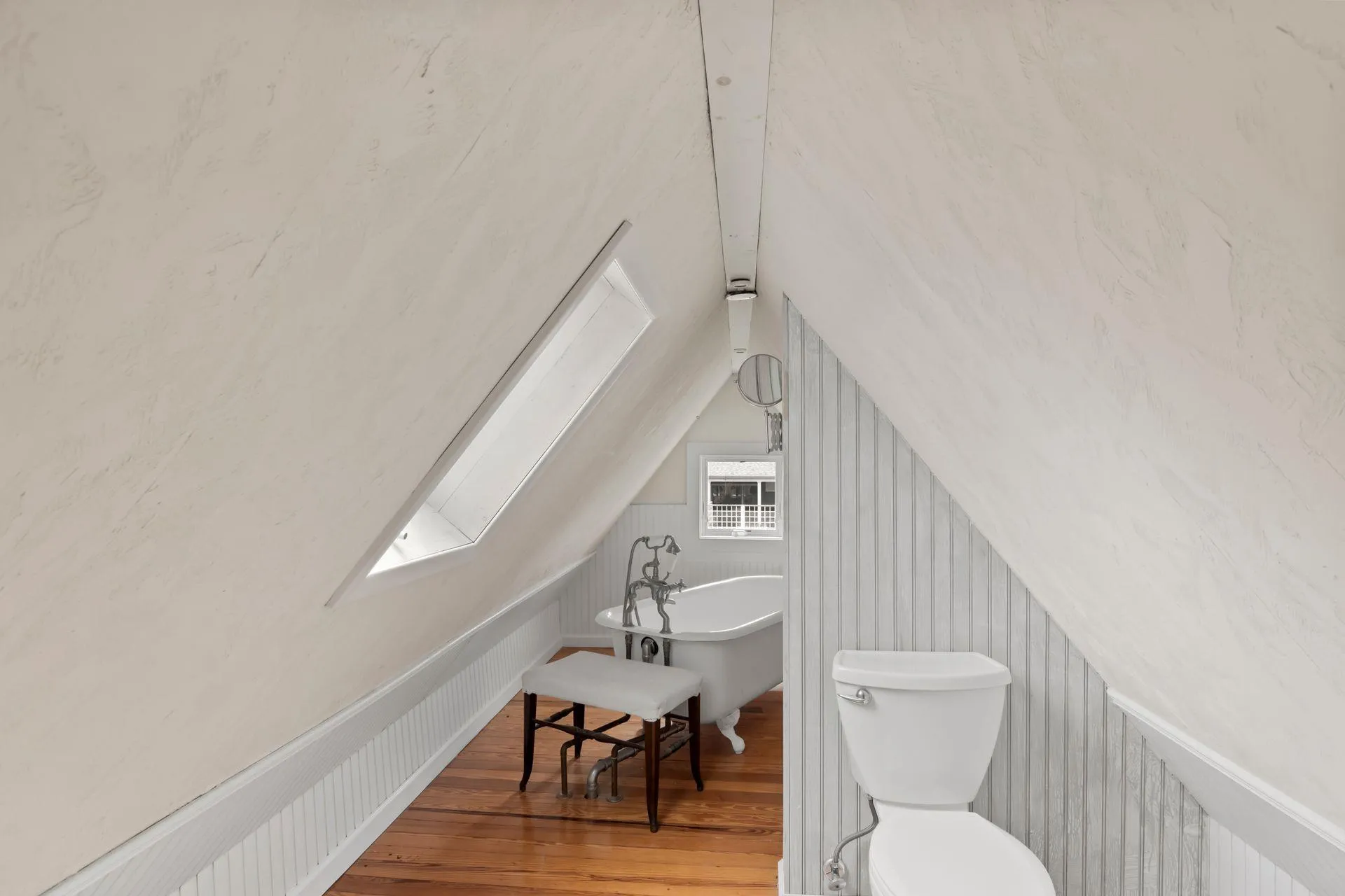 Bathroom with wood-type flooring, toilet, a bathing tub, and vaulted ceiling Bathroom with wood-type flooring, toilet, a bathing tub, and vaulted ceiling