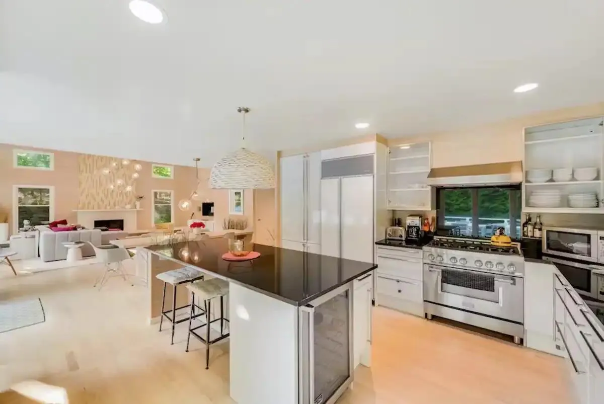 Kitchen featuring a fireplace, ventilation hood, white cabinets, a kitchen breakfast bar, and high end range Kitchen featuring a fireplace, ventilation hood, white cabinets, a kitchen breakfast bar, and high end range