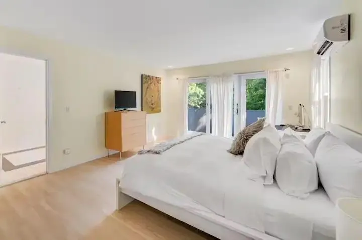 Bedroom with hardwood / wood-style floors, access to outside, and a wall mounted AC Bedroom with hardwood / wood-style floors, access to outside, and a wall mounted AC