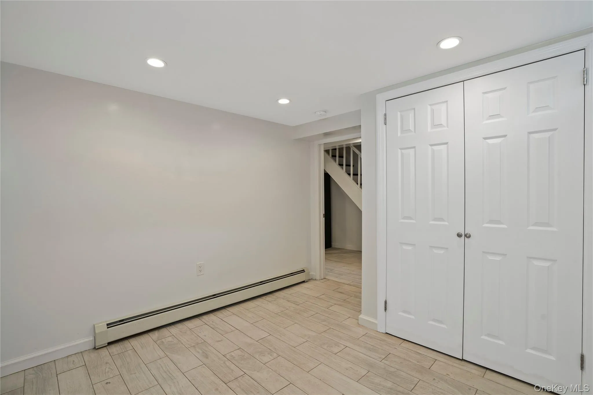 Unfurnished bedroom featuring a baseboard radiator, light wood finished floors, recessed lighting, and a closet Unfurnished bedroom featuring a baseboard radiator, light wood finished floors, recessed lighting, and a closet