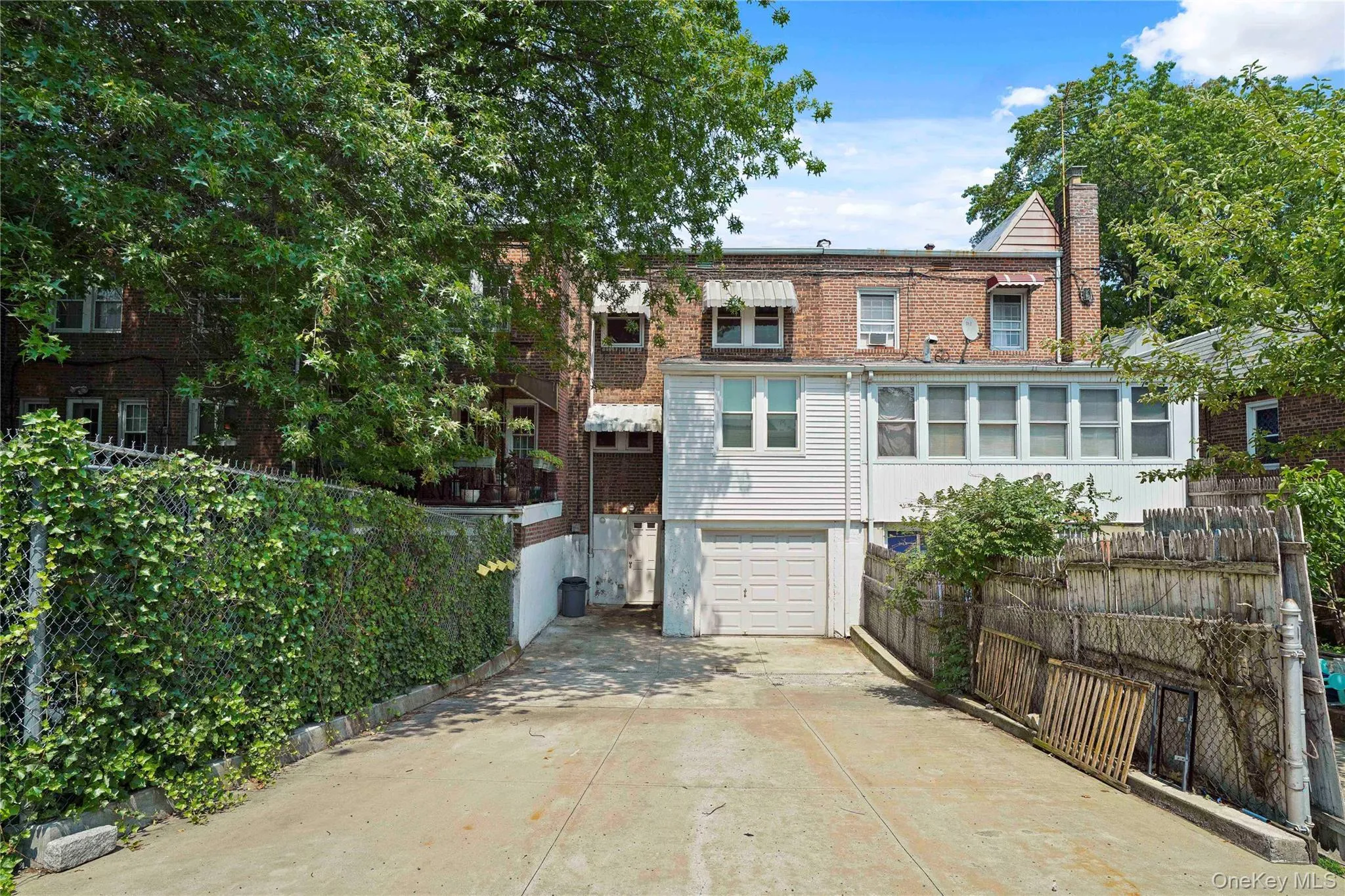 Back of house with an attached garage, concrete driveway, a chimney, and brick siding Back of house with an attached garage, concrete driveway, a chimney, and brick siding
