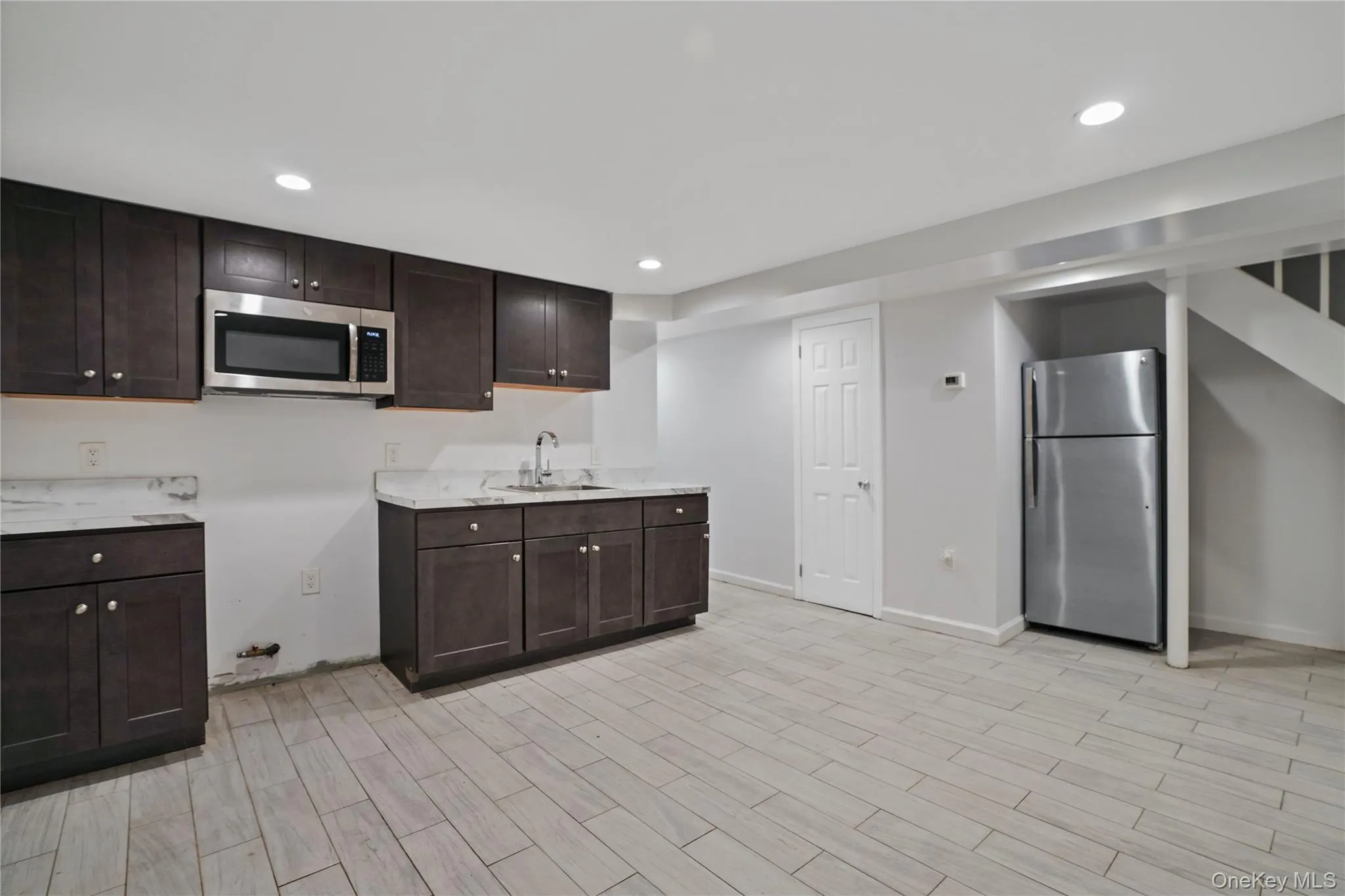 Kitchen with appliances with stainless steel finishes, dark brown cabinetry, recessed lighting, and light wood-type flooring Kitchen with appliances with stainless steel finishes, dark brown cabinetry, recessed lighting, and light wood-type flooring