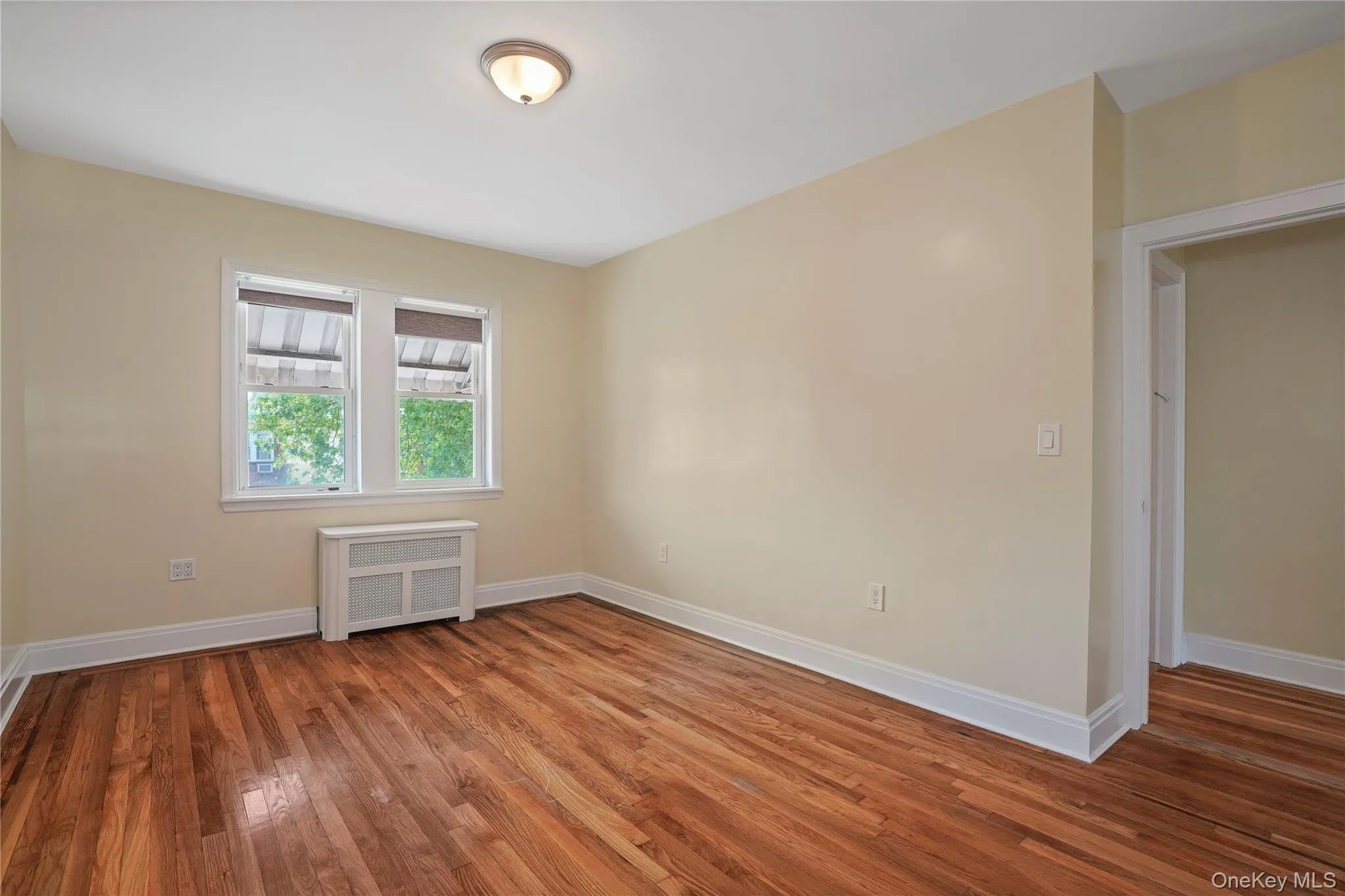 Empty room with radiator heating unit and hardwood / wood-style floors Empty room with radiator heating unit and hardwood / wood-style floors