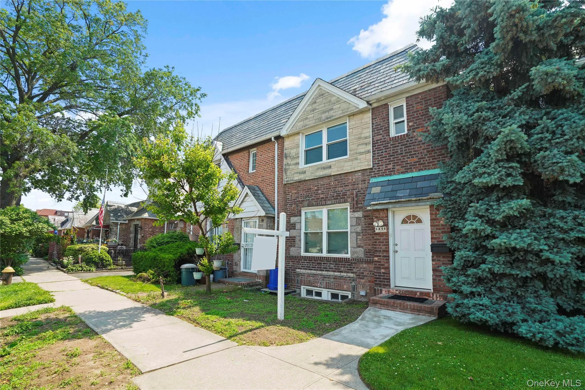 Townhome / multi-family property with a high end roof, a front lawn, and brick siding Townhome / multi-family property with a high end roof, a front lawn, and brick siding