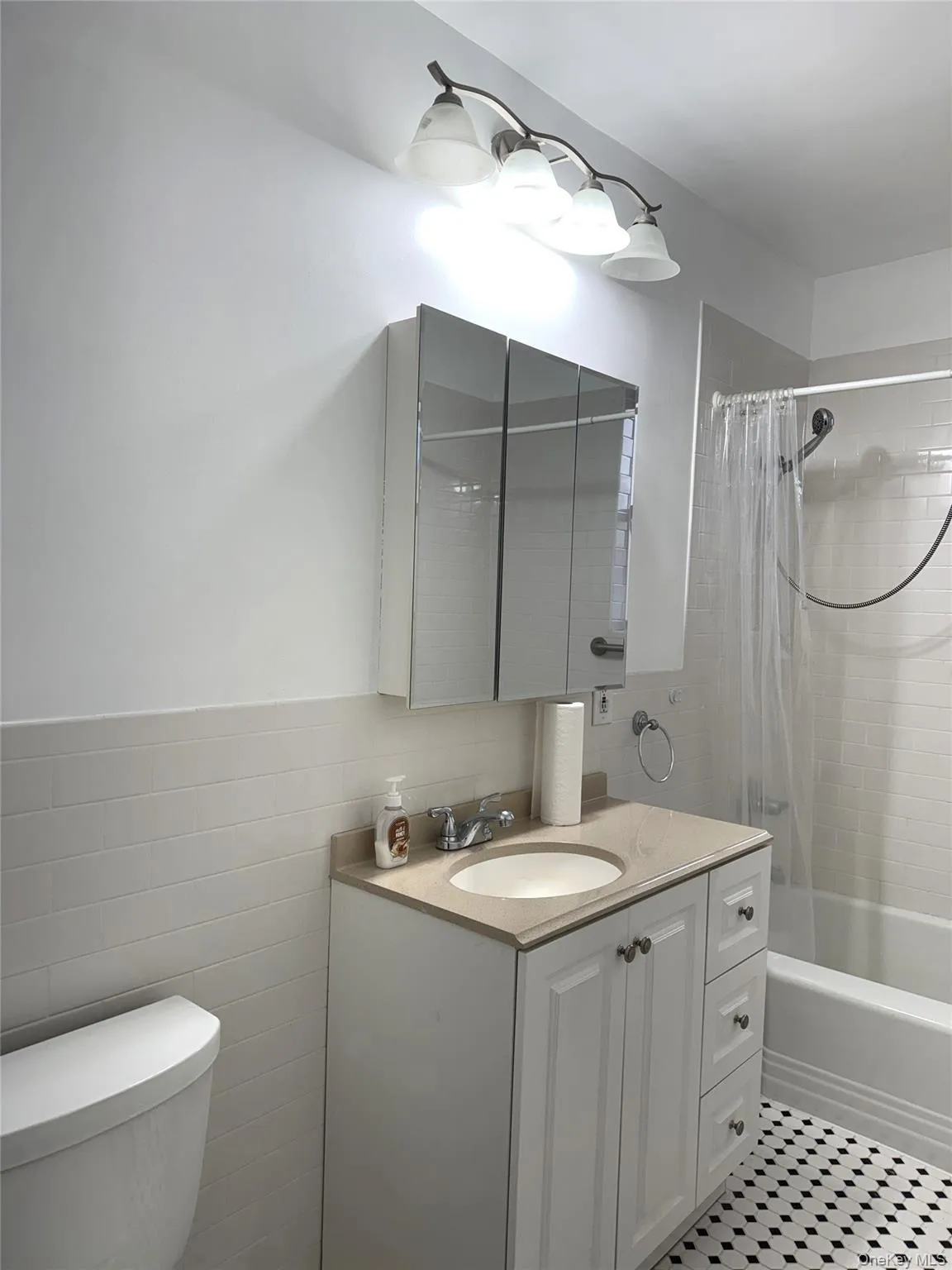 Full bathroom featuring tile walls, vanity, shower / bath combination with curtain, and toilet Full bathroom featuring tile walls, vanity, shower / bath combination with curtain, and toilet