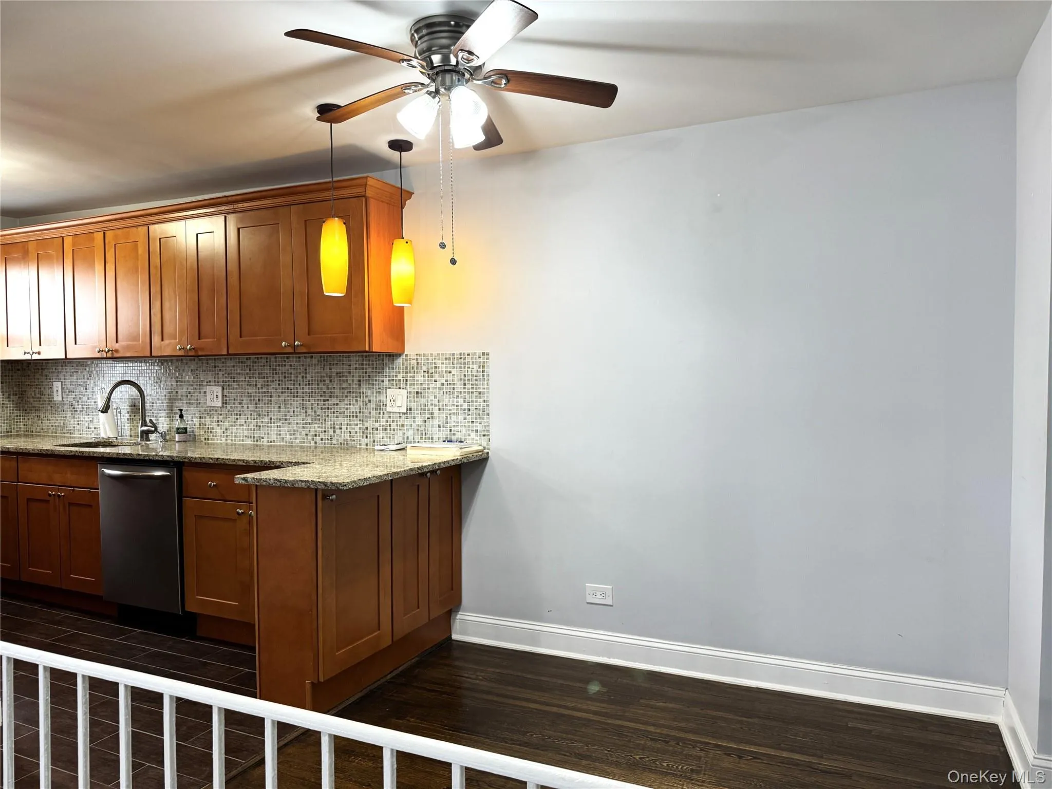 Kitchen with dark hardwood / wood-style floors, dishwasher, sink, backsplash, and light stone counters Kitchen with dark hardwood / wood-style floors, dishwasher, sink, backsplash, and light stone counters