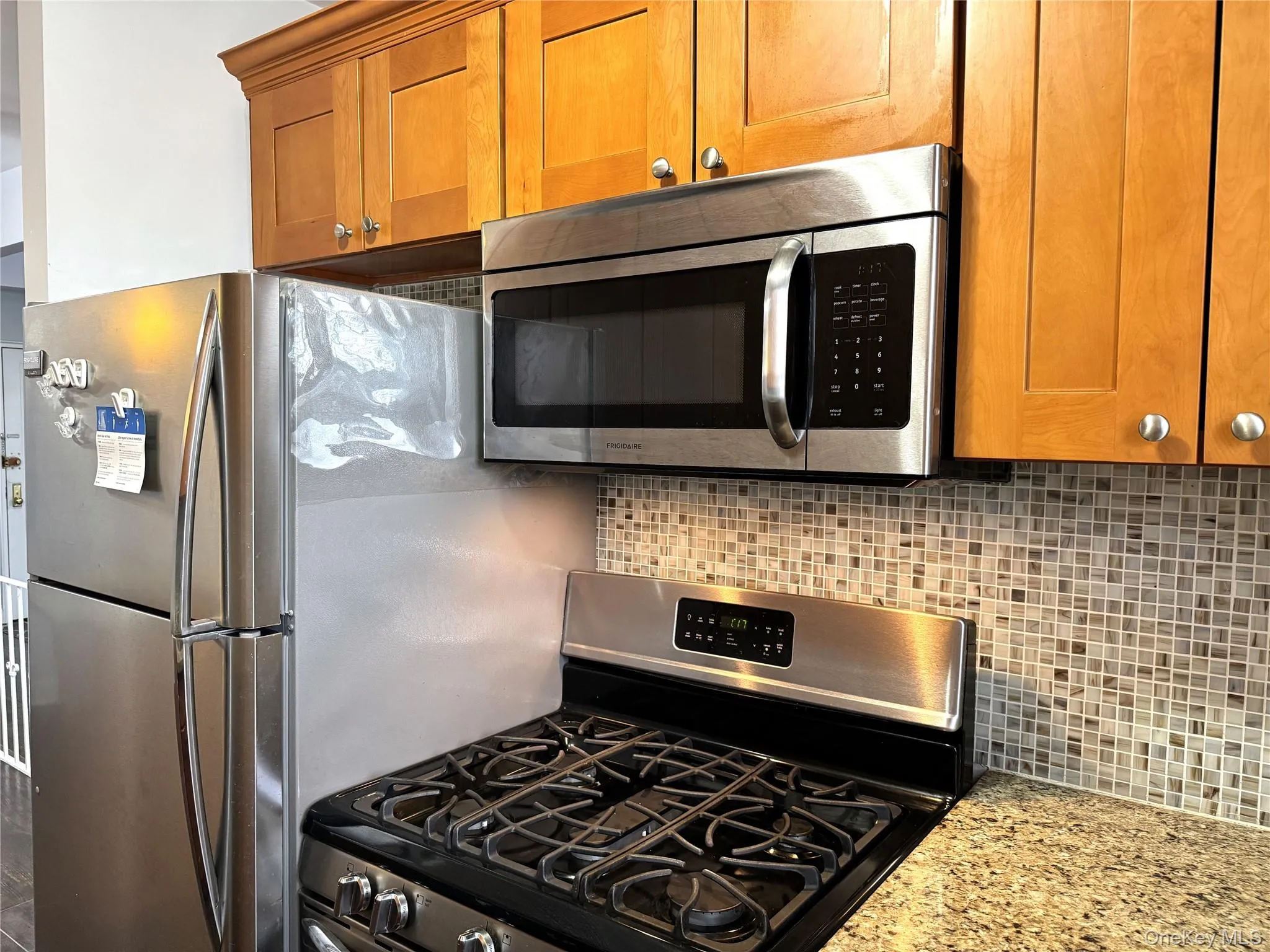Kitchen featuring stainless steel appliances, backsplash, and light stone counters Kitchen featuring stainless steel appliances, backsplash, and light stone counters