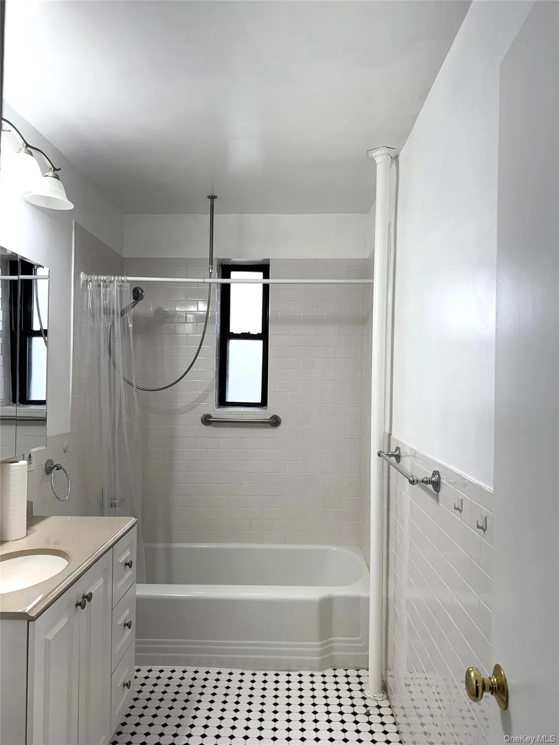 Bathroom featuring shower / bath combo with shower curtain, vanity, tile patterned flooring, and tile walls Bathroom featuring shower / bath combo with shower curtain, vanity, tile patterned flooring, and tile walls