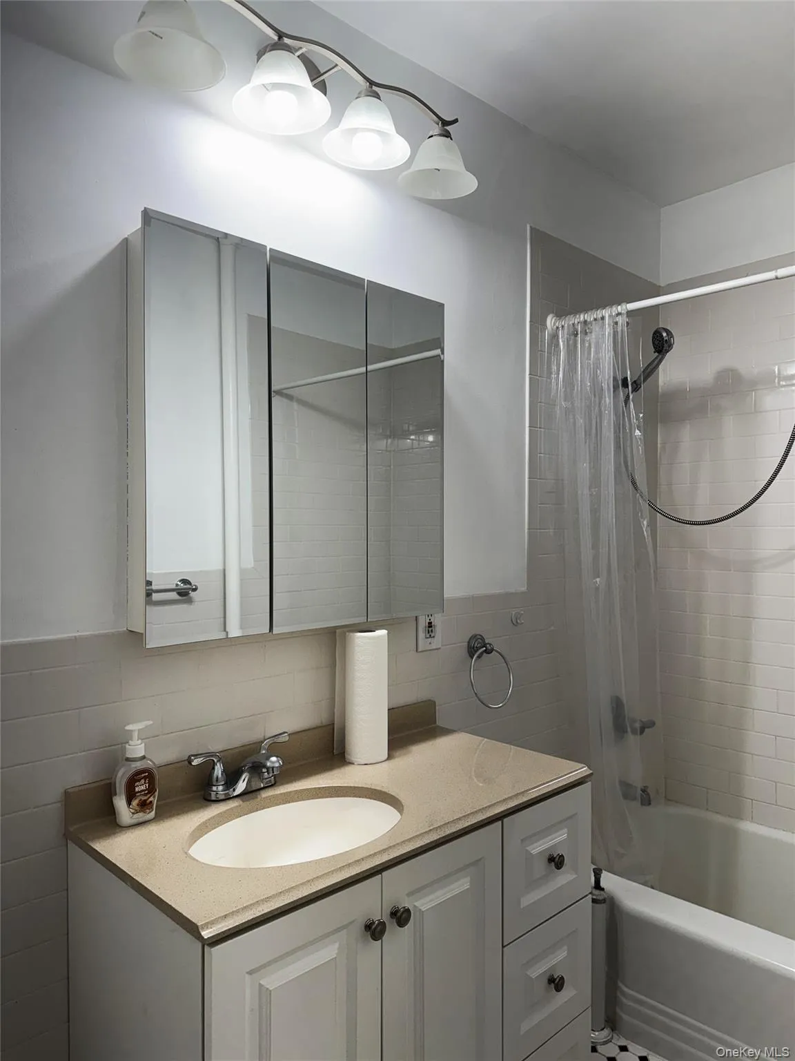 Bathroom featuring tile walls, shower / tub combo, and vanity Bathroom featuring tile walls, shower / tub combo, and vanity