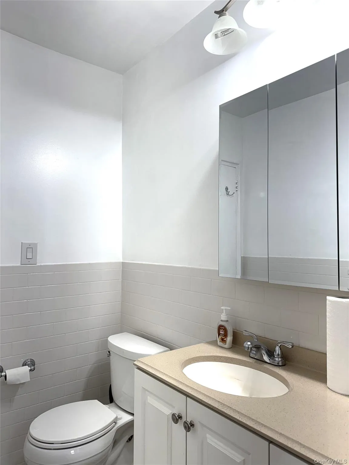 Bathroom featuring vanity, tile walls, and toilet Bathroom featuring vanity, tile walls, and toilet