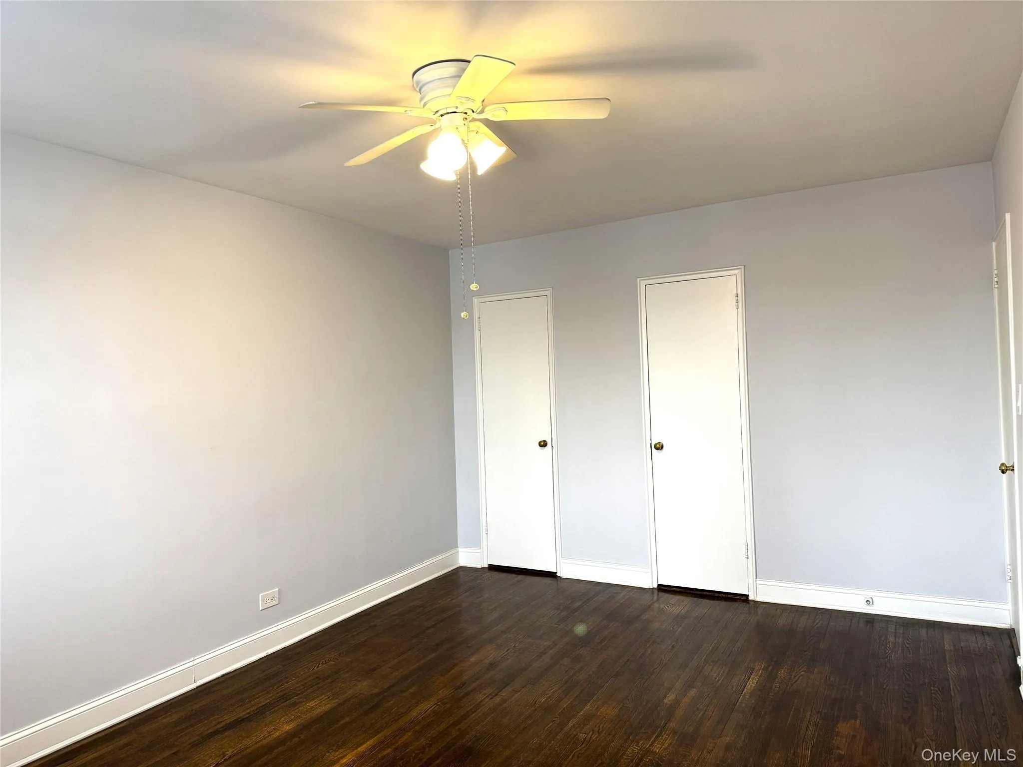 Unfurnished bedroom featuring dark wood-type flooring and ceiling fan Unfurnished bedroom featuring dark wood-type flooring and ceiling fan