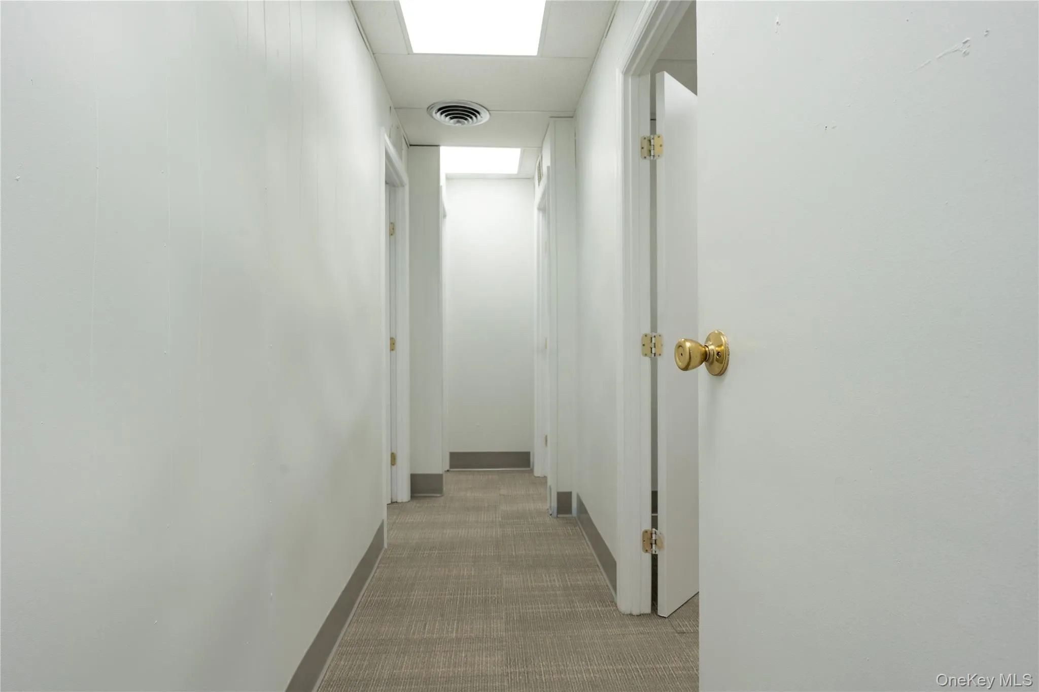 Hall featuring light carpet and baseboards Hall featuring light carpet and baseboards