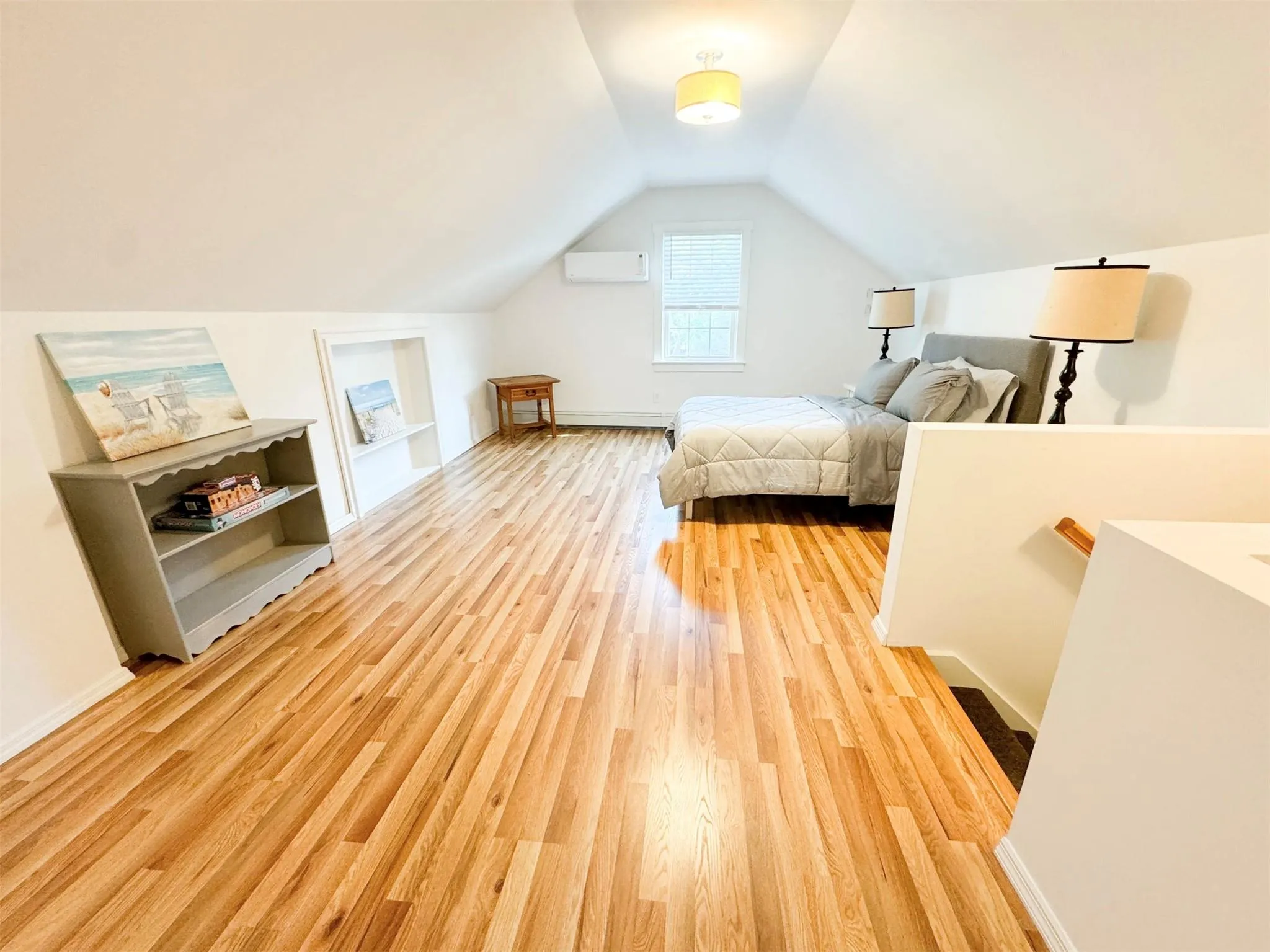 Bedroom with vaulted ceiling, a wall mounted AC, and light wood-type flooring Bedroom with vaulted ceiling, a wall mounted AC, and light wood-type flooring