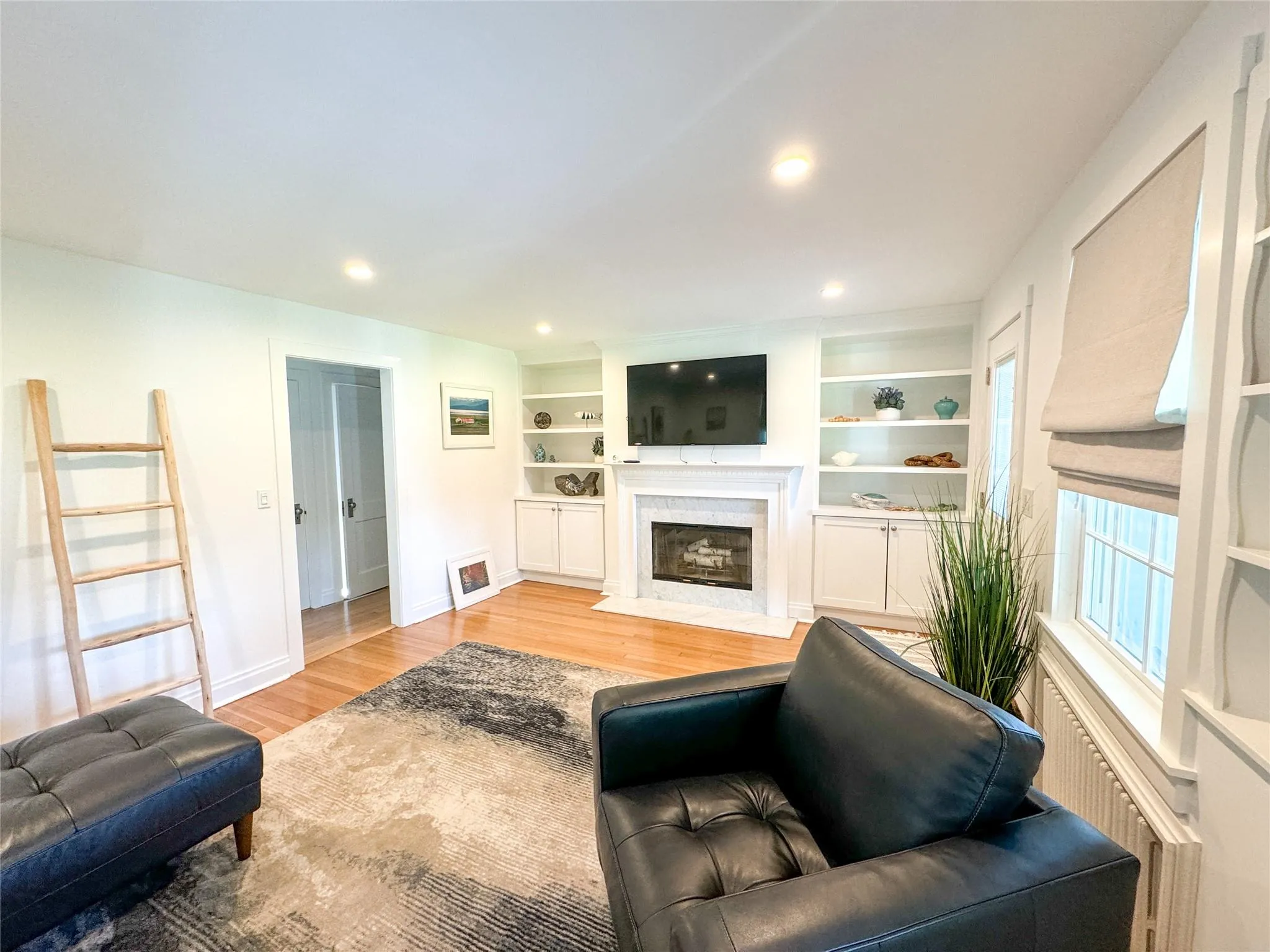 Living room with built in features and light hardwood / wood-style flooring Living room with built in features and light hardwood / wood-style flooring
