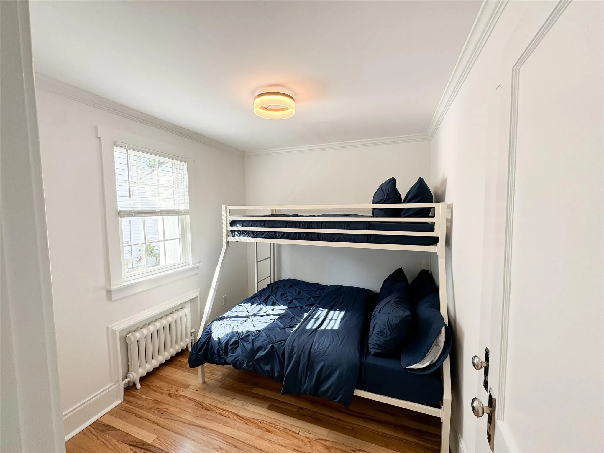 Bedroom with ornamental molding, radiator, and hardwood / wood-style floors Bedroom with ornamental molding, radiator, and hardwood / wood-style floors