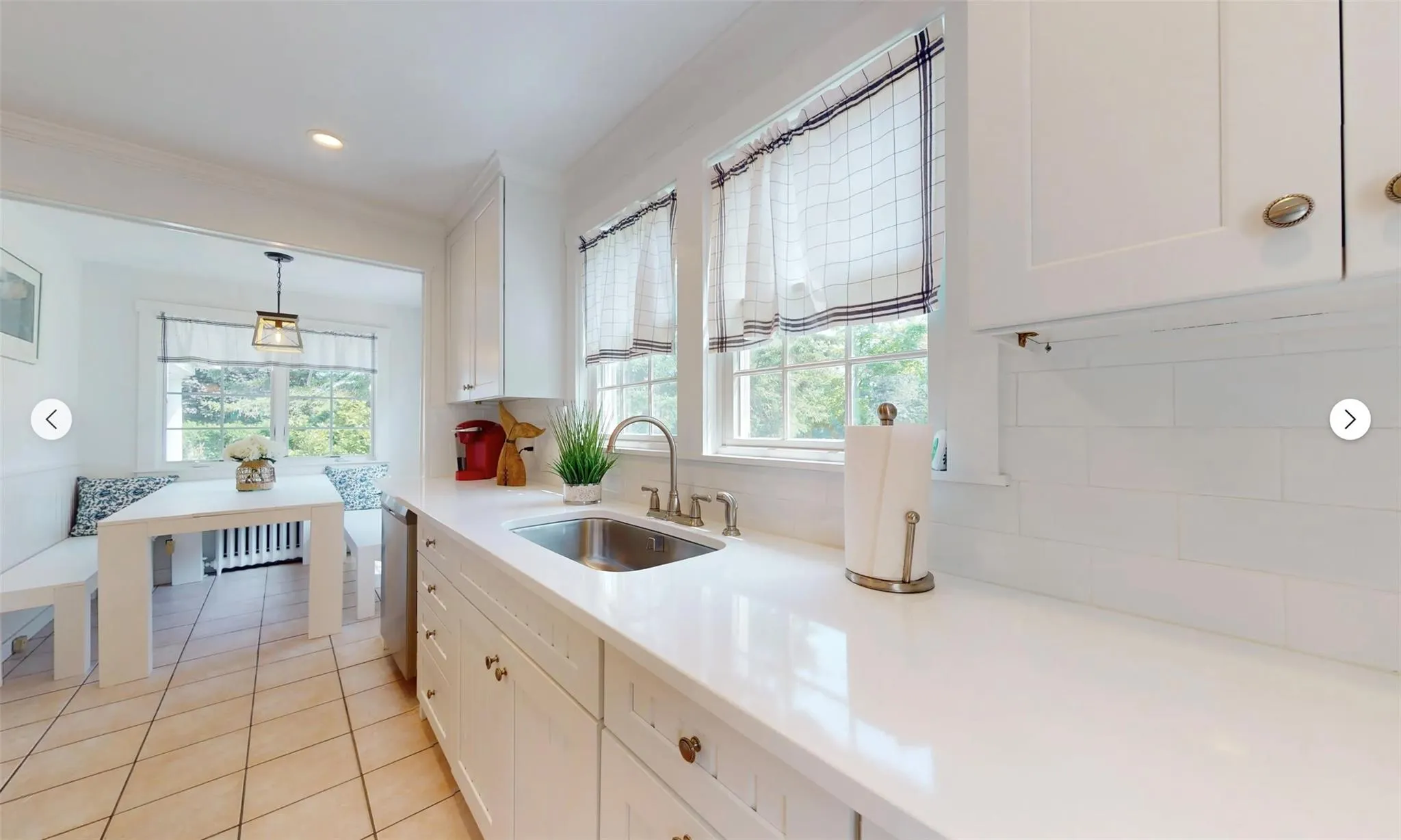 Kitchen with dishwasher, sink, white cabinets, and decorative light fixtures Kitchen with dishwasher, sink, white cabinets, and decorative light fixtures