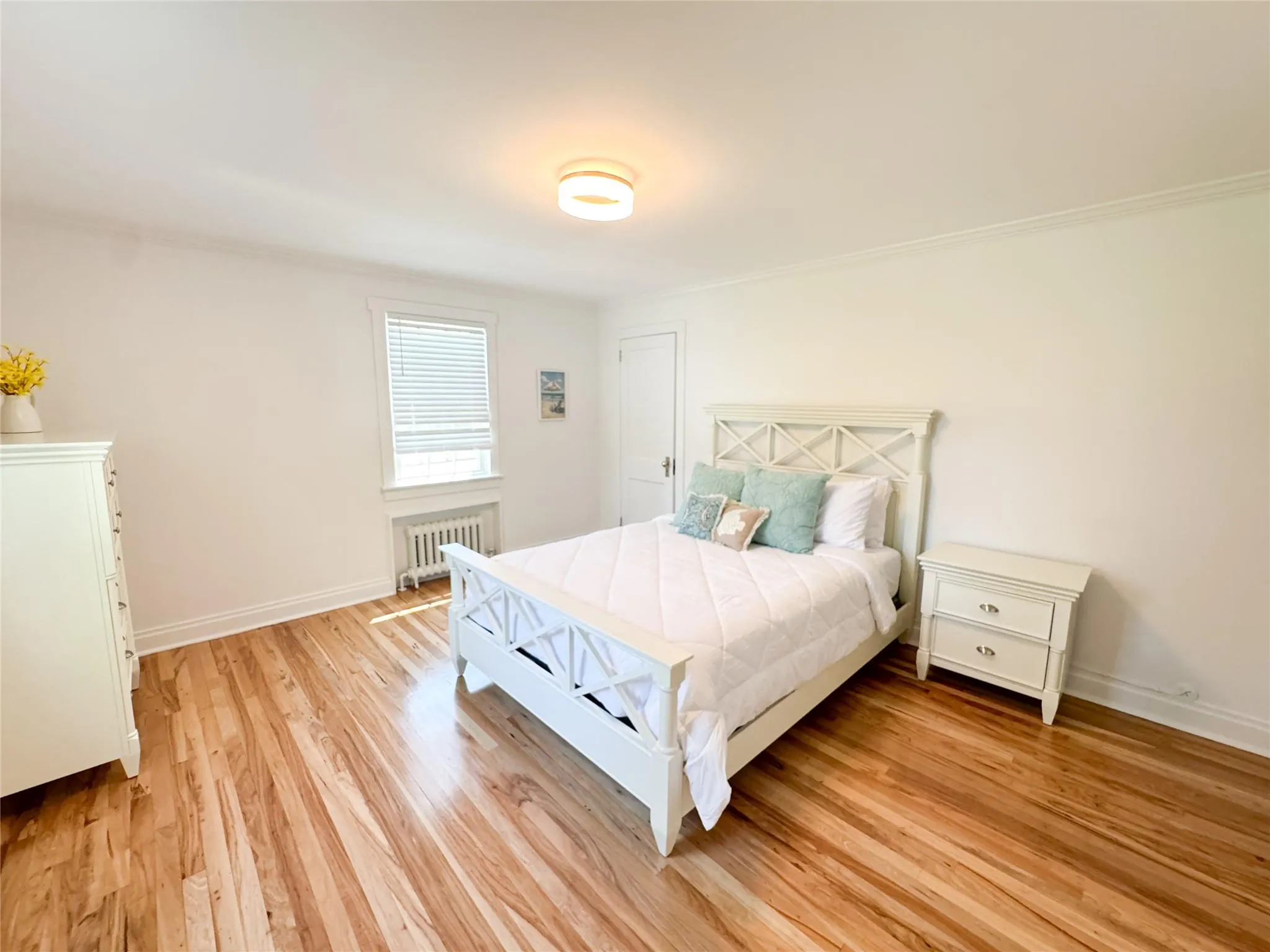 Bedroom with radiator, crown molding, and light hardwood / wood-style flooring Bedroom with radiator, crown molding, and light hardwood / wood-style flooring