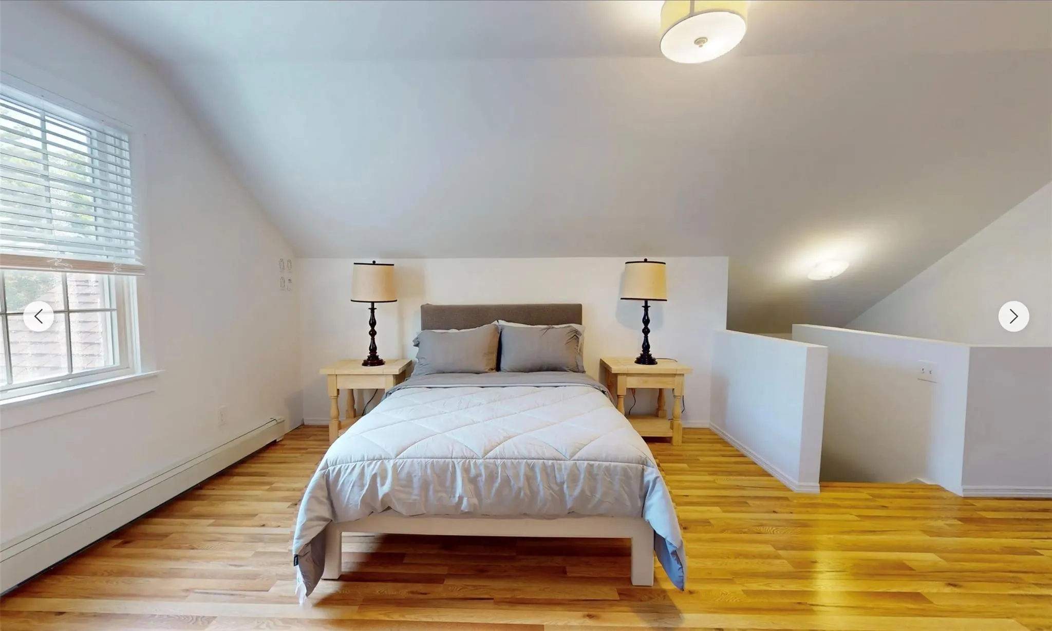 Bedroom featuring a baseboard heating unit, vaulted ceiling, and light wood-type flooring Bedroom featuring a baseboard heating unit, vaulted ceiling, and light wood-type flooring