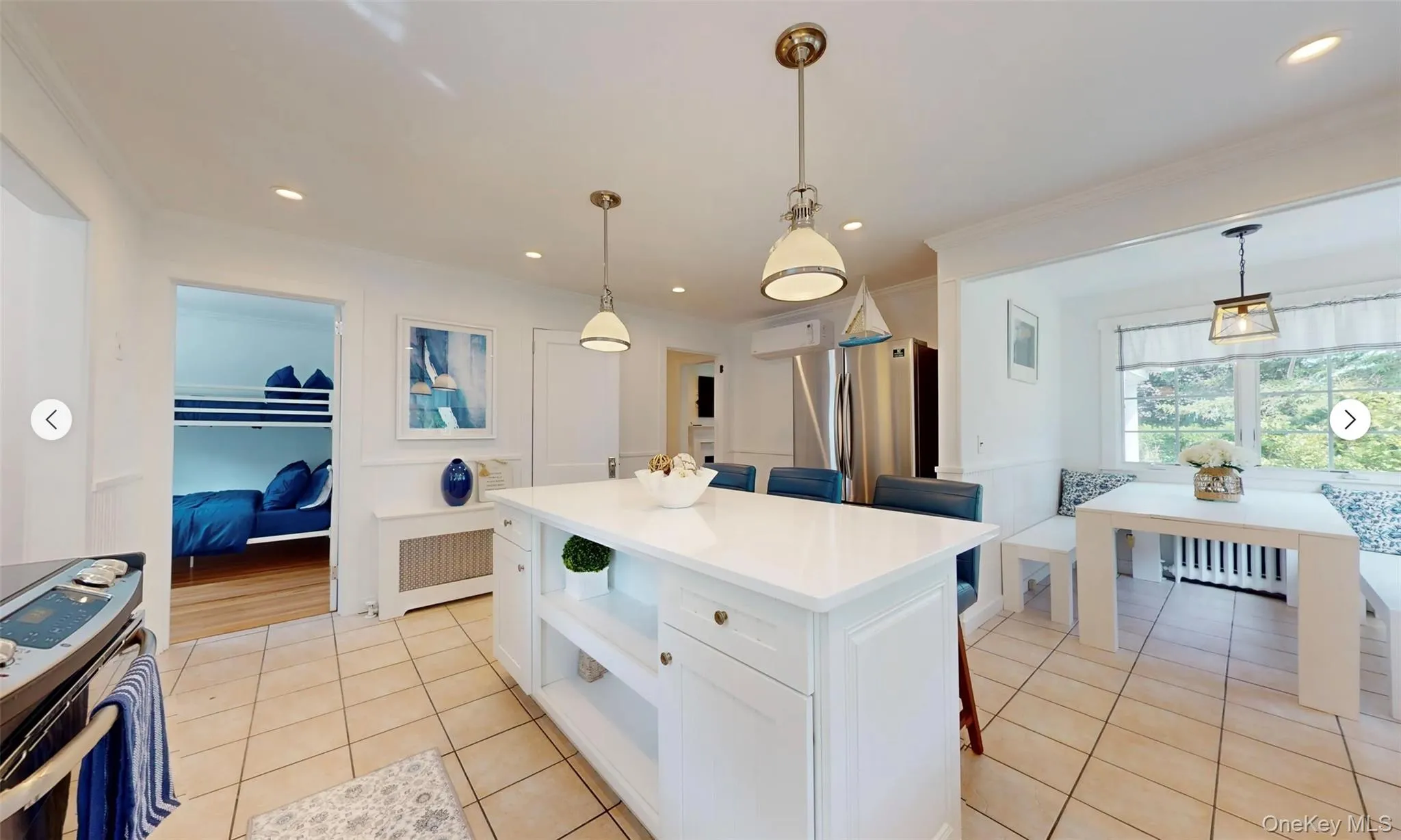 Kitchen featuring stainless steel appliances, white cabinetry, hanging light fixtures, and radiator Kitchen featuring stainless steel appliances, white cabinetry, hanging light fixtures, and radiator