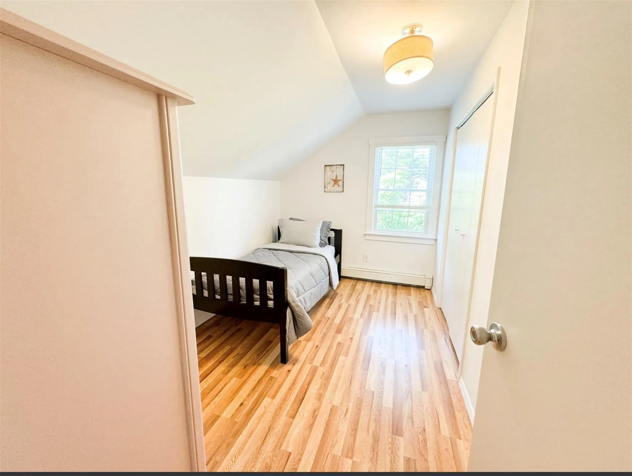 Bedroom featuring lofted ceiling, baseboard heating, and light wood-type flooring Bedroom featuring lofted ceiling, baseboard heating, and light wood-type flooring