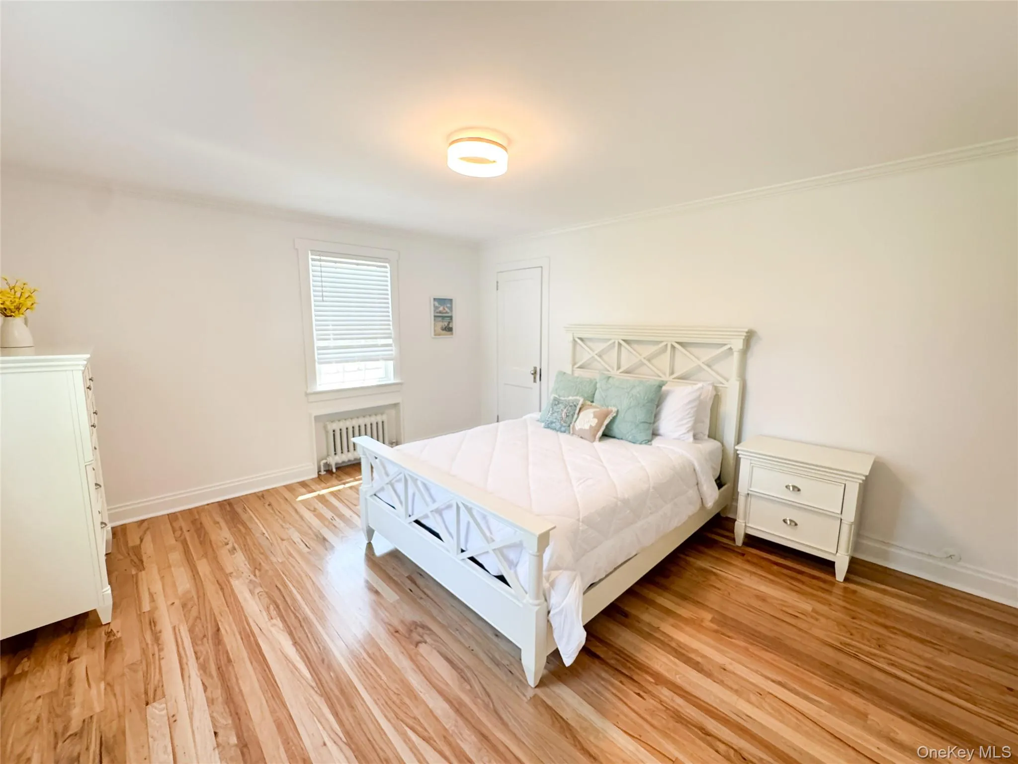 Bedroom with radiator, crown molding, and light hardwood / wood-style flooring Bedroom with radiator, crown molding, and light hardwood / wood-style flooring