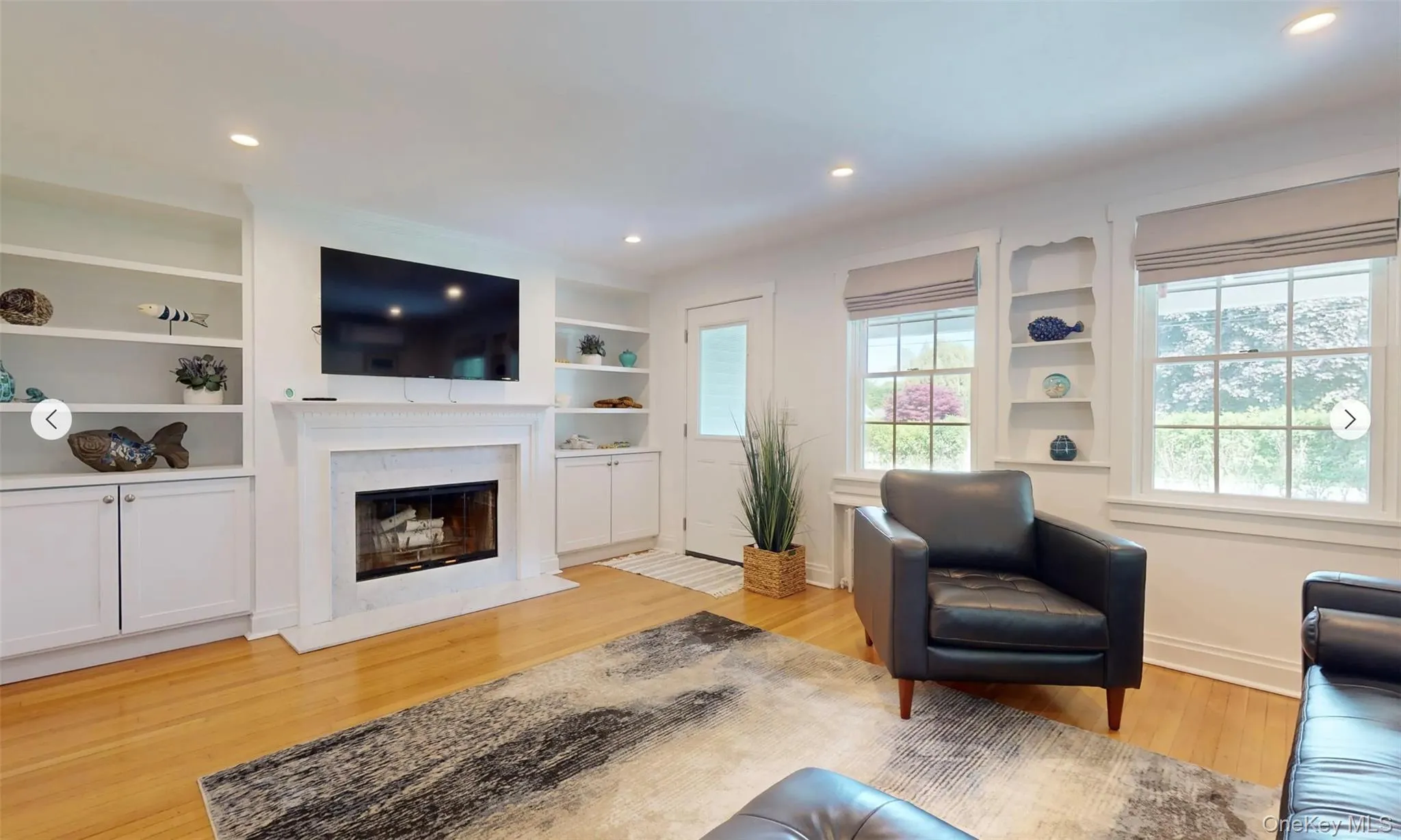 Living room with built in features, a high end fireplace, and light hardwood / wood-style floors Living room with built in features, a high end fireplace, and light hardwood / wood-style floors
