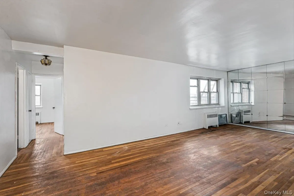 Unfurnished living room with dark wood-type flooring, radiator, and a wealth of natural light Unfurnished living room with dark wood-type flooring, radiator, and a wealth of natural light