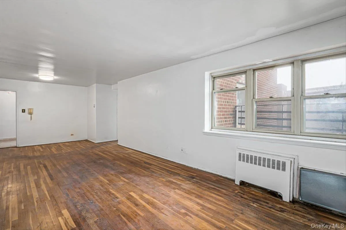 Spare room featuring dark hardwood / wood-style floors and radiator heating unit Spare room featuring dark hardwood / wood-style floors and radiator heating unit