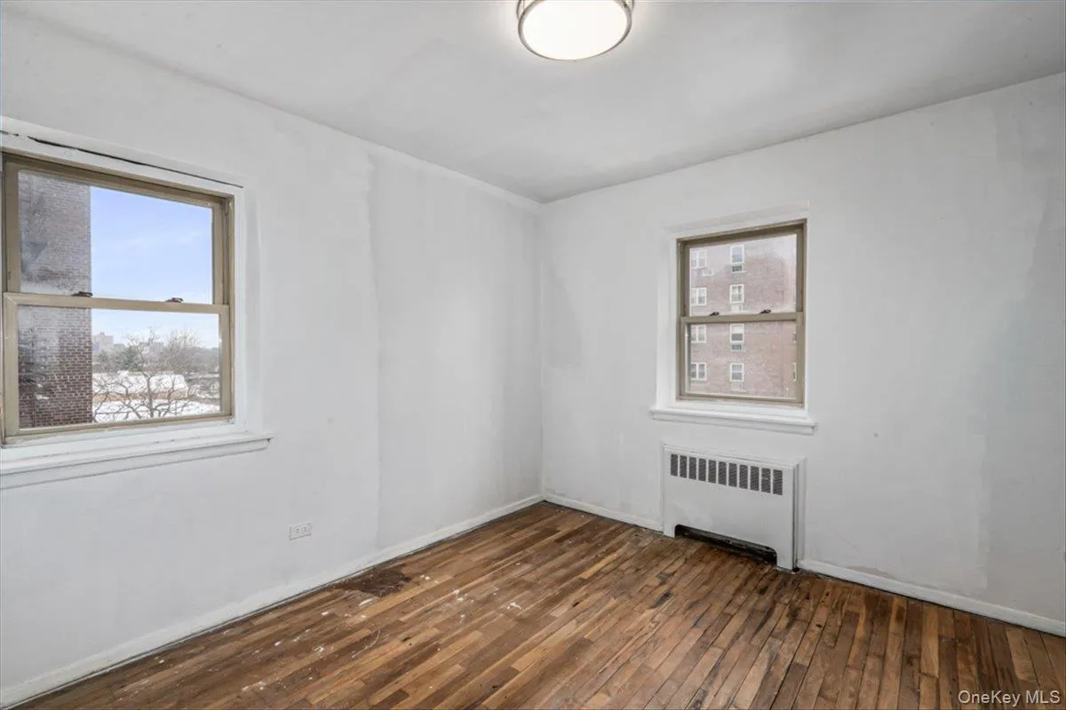 Spare room featuring dark hardwood / wood-style flooring and radiator Spare room featuring dark hardwood / wood-style flooring and radiator