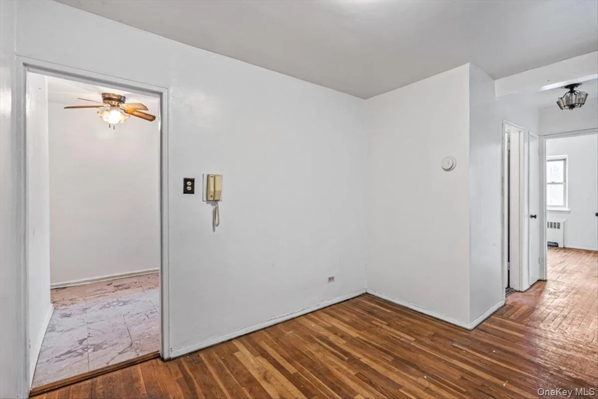 Empty room with dark hardwood / wood-style floors, radiator heating unit, and ceiling fan Empty room with dark hardwood / wood-style floors, radiator heating unit, and ceiling fan