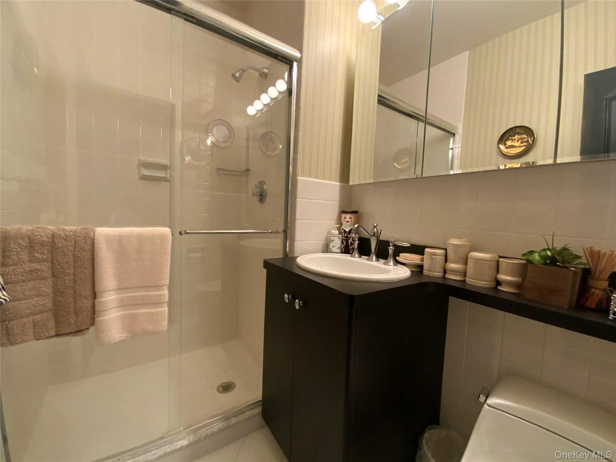 Bathroom with decorative backsplash, tile walls, vanity, and a stall shower Bathroom with decorative backsplash, tile walls, vanity, and a stall shower
