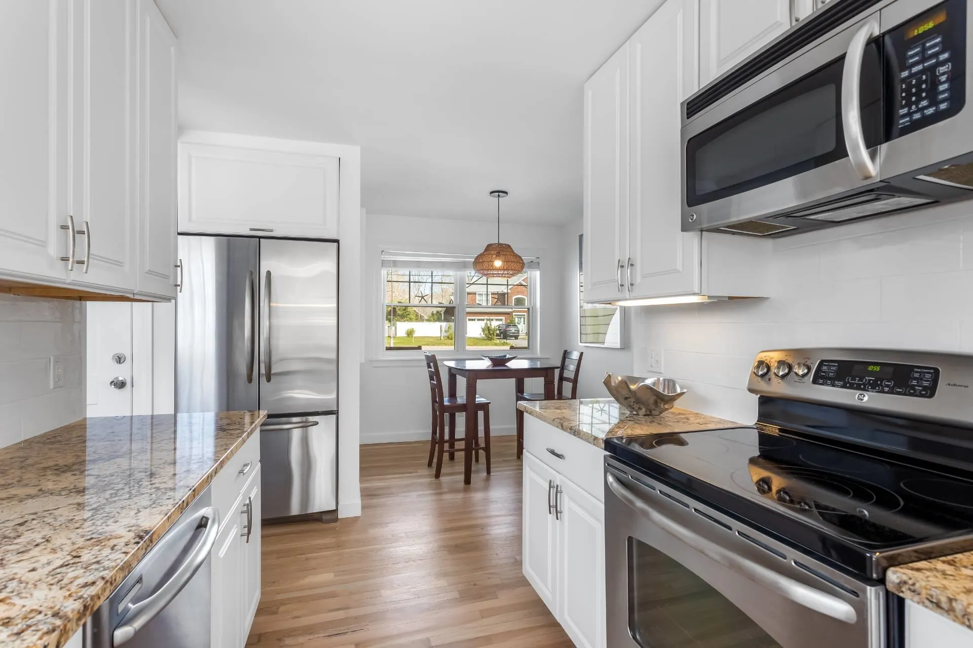 Kitchen featuring white cabinetry, hanging light fixtures, and stainless steel appliances Kitchen featuring white cabinetry, hanging light fixtures, and stainless steel appliances