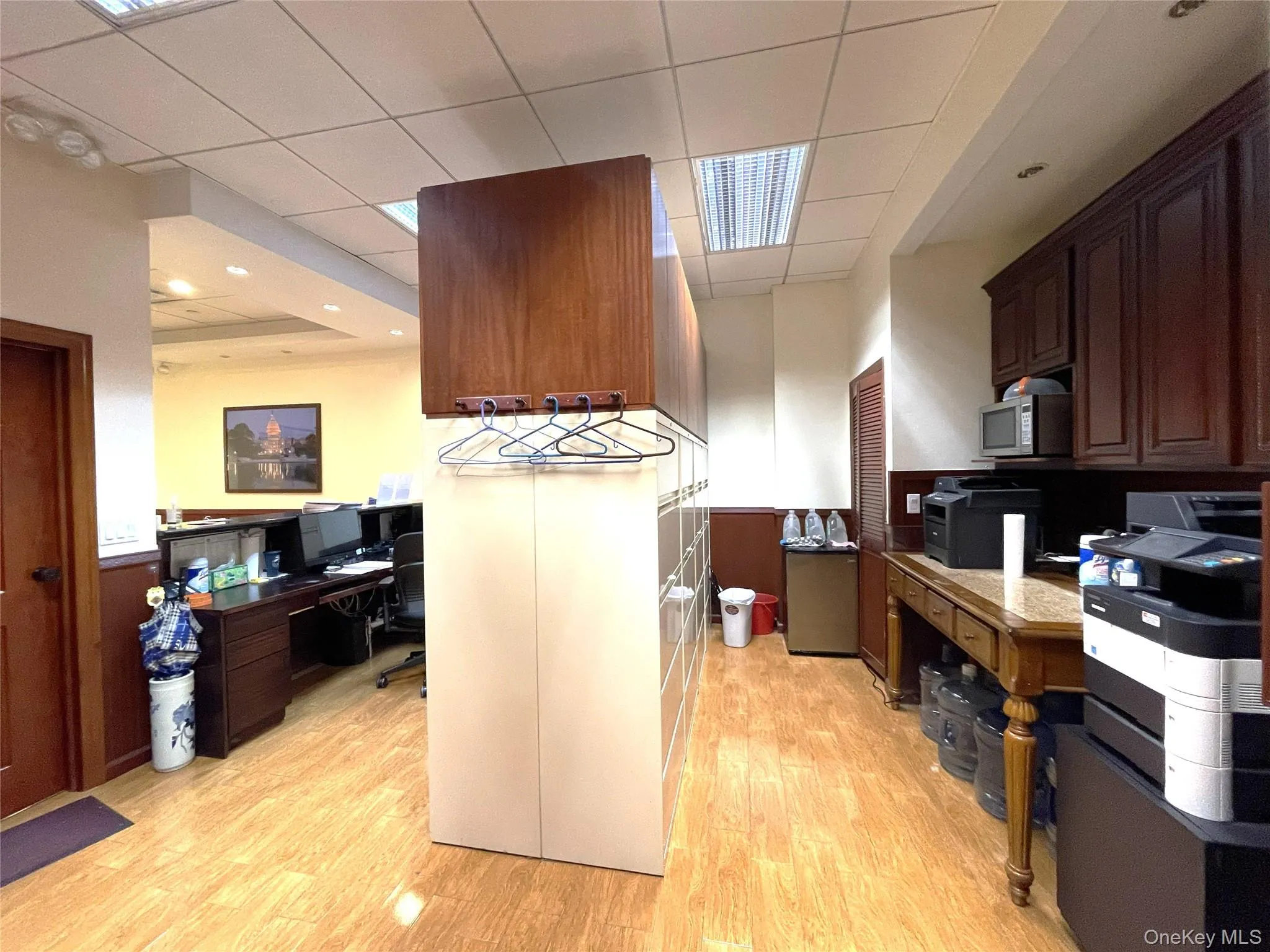 Kitchen featuring an office area, light wood finished floors, a drop ceiling, light countertops, and stainless steel microwave Kitchen featuring an office area, light wood finished floors, a drop ceiling, light countertops, and stainless steel microwave