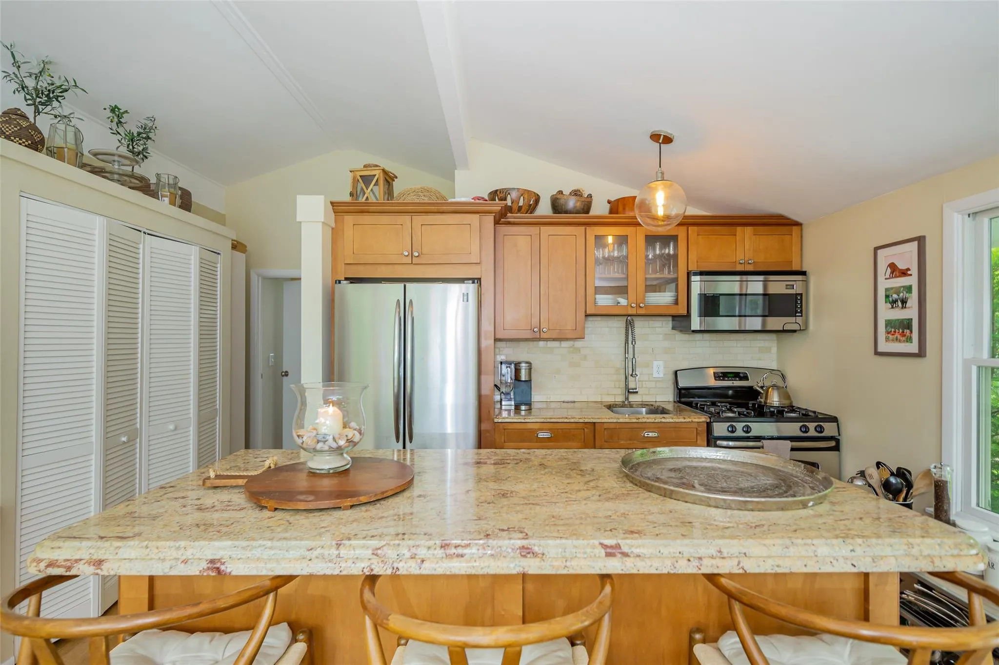 Kitchen with stainless steel appliances, a sink, decorative backsplash, lofted ceiling with beams, and glass insert cabinets Kitchen with stainless steel appliances, a sink, decorative backsplash, lofted ceiling with beams, and glass insert cabinets