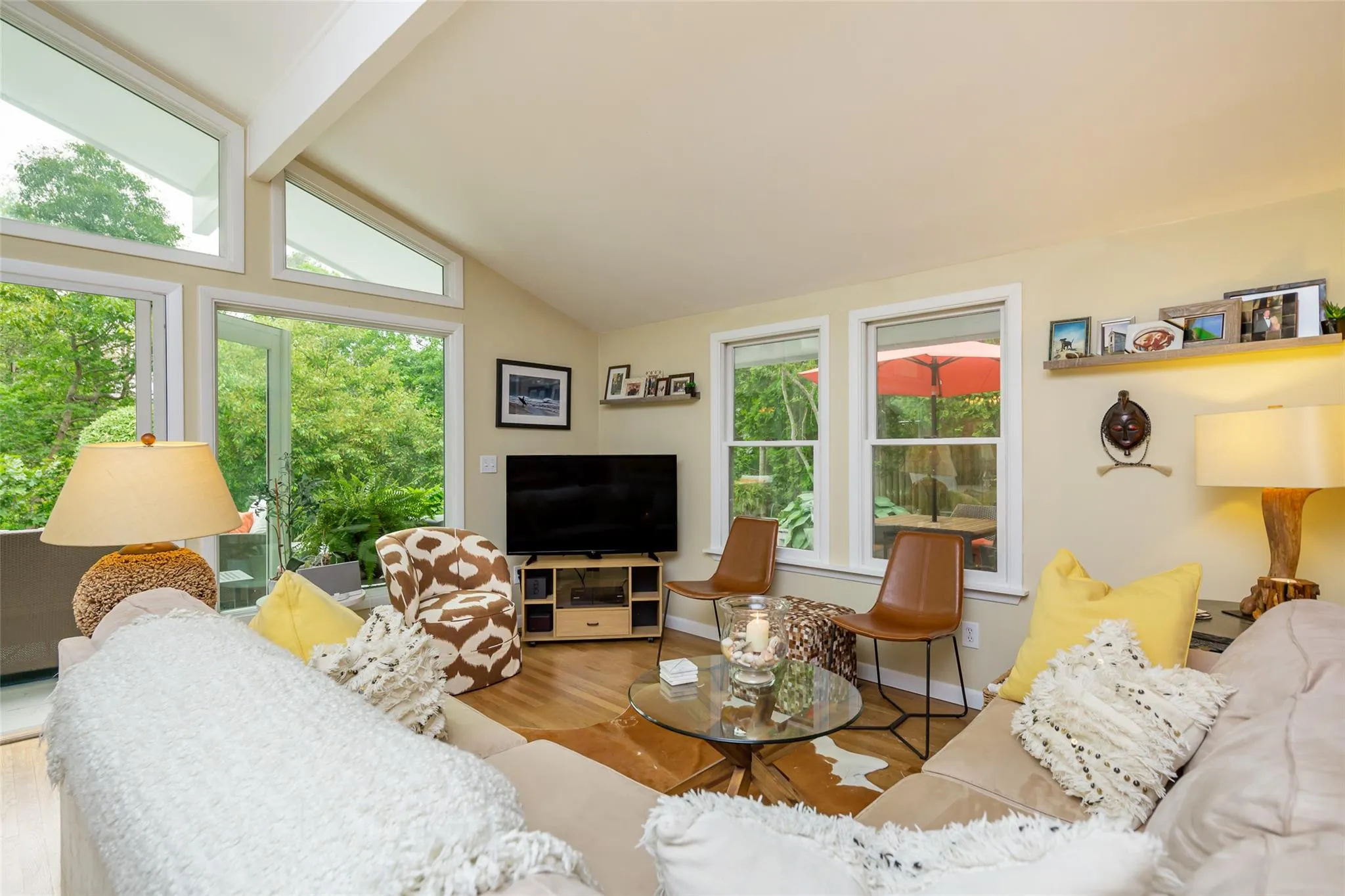 Living room featuring wood finished floors, vaulted ceiling with beams, and plenty of natural light Living room featuring wood finished floors, vaulted ceiling with beams, and plenty of natural light