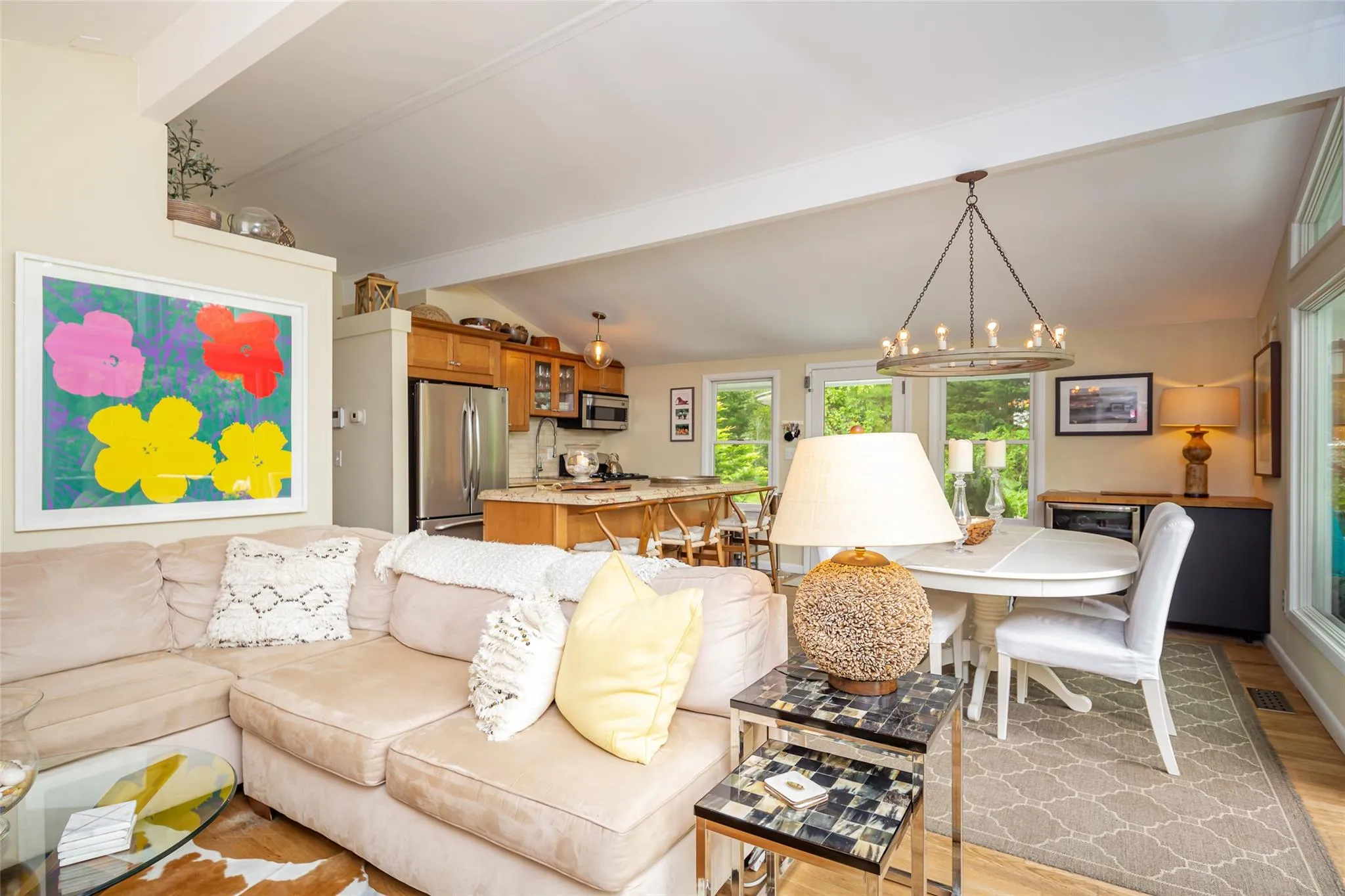 Living room with light wood-style flooring, visible vents, vaulted ceiling with beams, and a notable chandelier Living room with light wood-style flooring, visible vents, vaulted ceiling with beams, and a notable chandelier