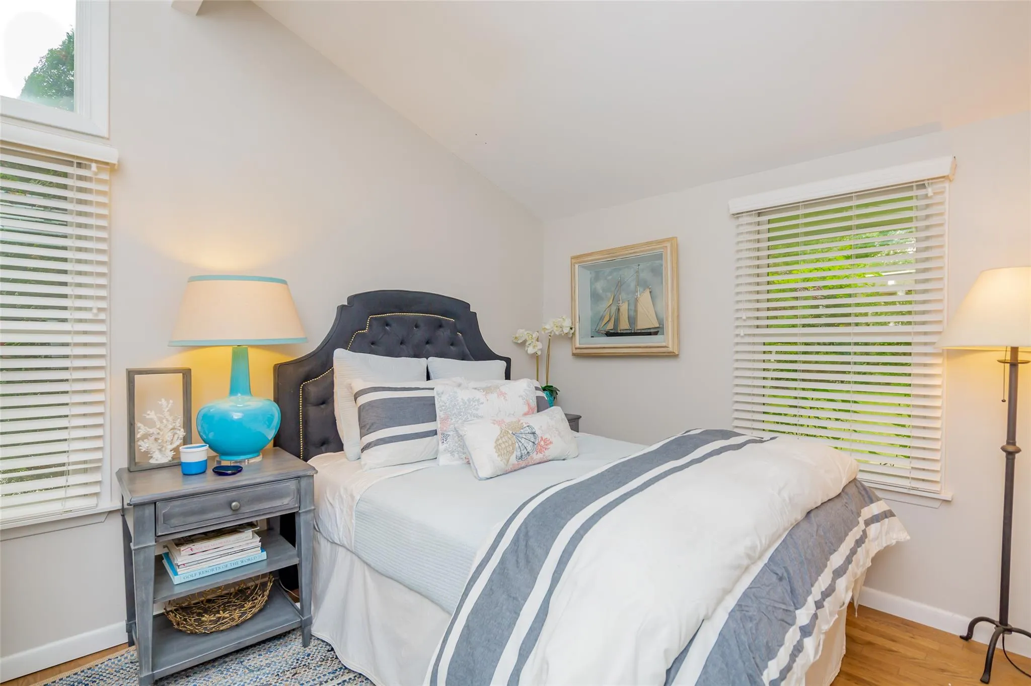 Bedroom featuring multiple windows, vaulted ceiling, baseboards, and wood finished floors Bedroom featuring multiple windows, vaulted ceiling, baseboards, and wood finished floors