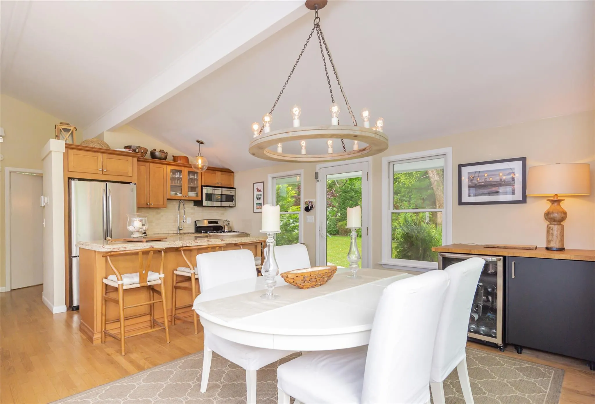 Dining area featuring beverage cooler, vaulted ceiling with beams, light wood-type flooring, a dry bar, and a notable chandelier Dining area featuring beverage cooler, vaulted ceiling with beams, light wood-type flooring, a dry bar, and a notable chandelier