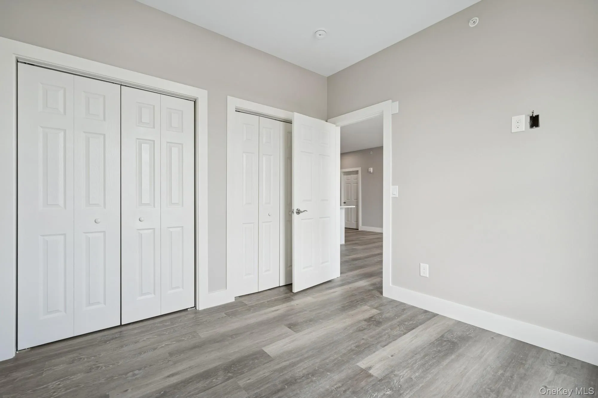 Unfurnished bedroom featuring two closets and wood finished floors Unfurnished bedroom featuring two closets and wood finished floors