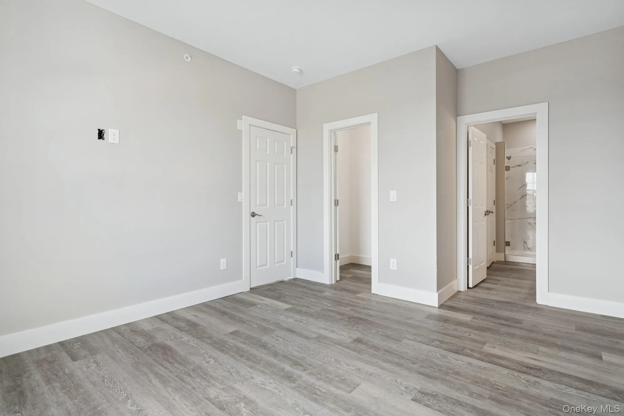 Unfurnished bedroom with light wood-type flooring and ensuite bath Unfurnished bedroom with light wood-type flooring and ensuite bath